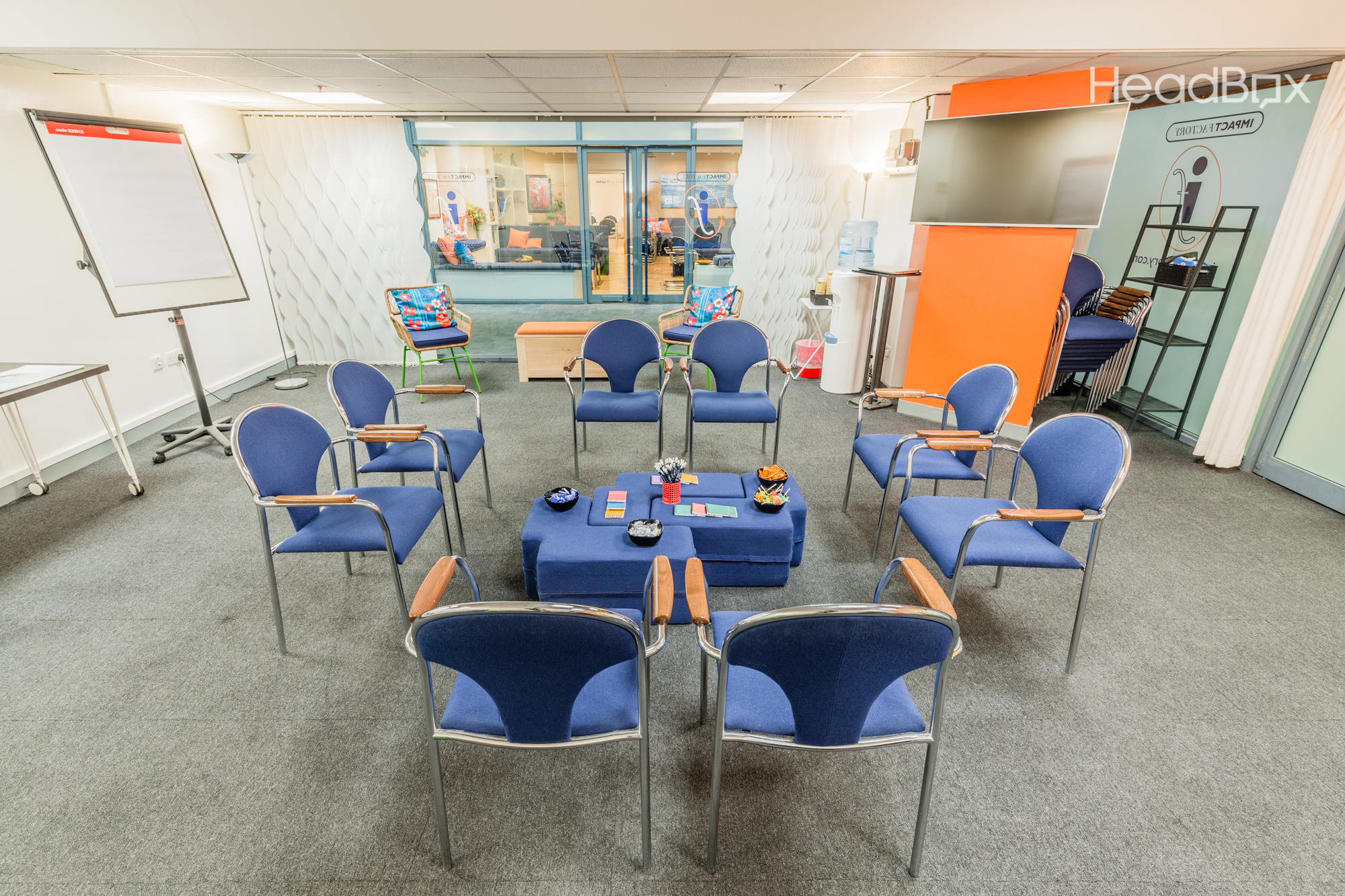Impact Factory's White Room with blue chairs, ideal for collaborative meetings.