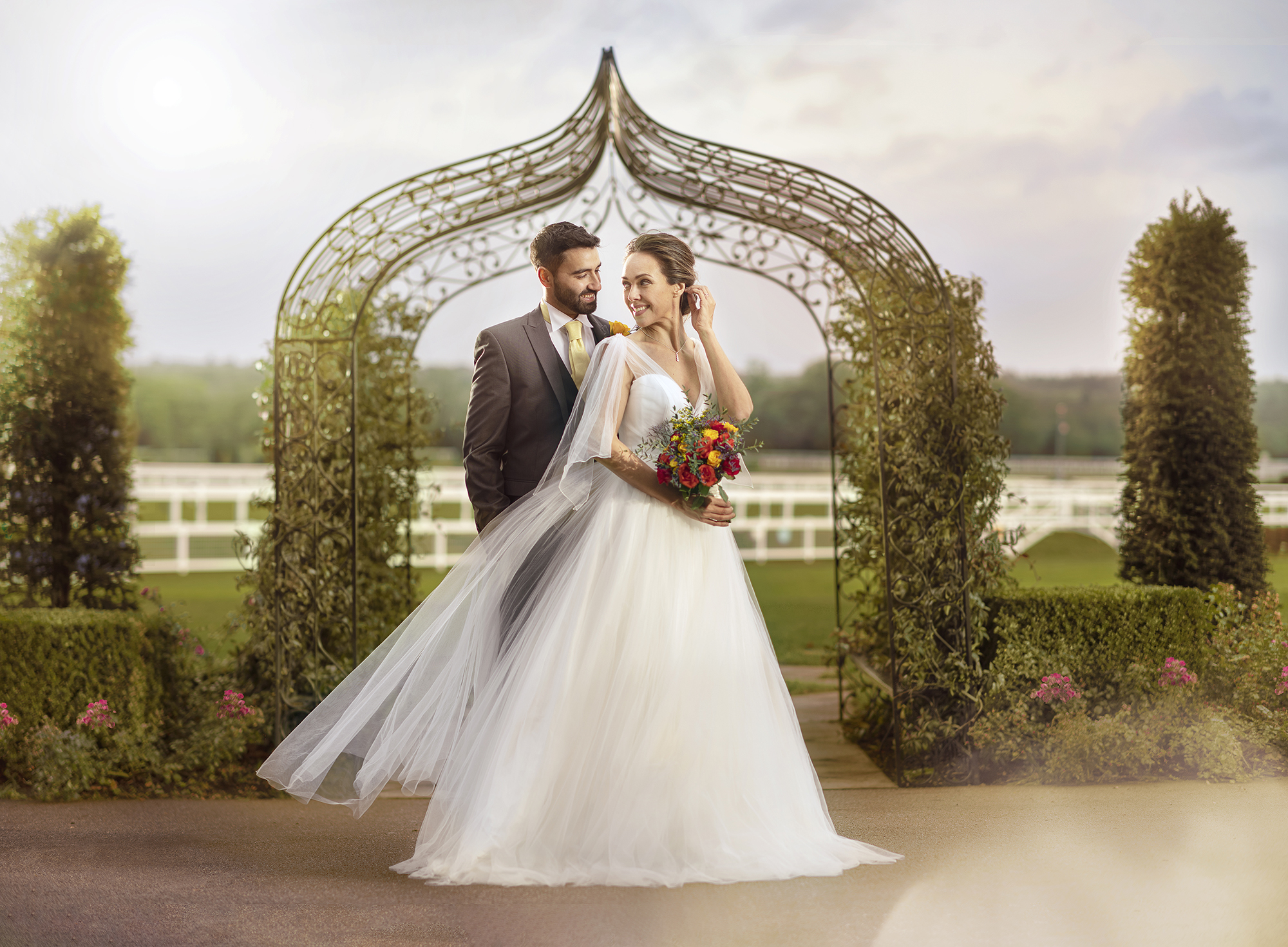 Outdoor wedding at The Furlong Suite, Ascot Racecourse, with elegant couple under archway.