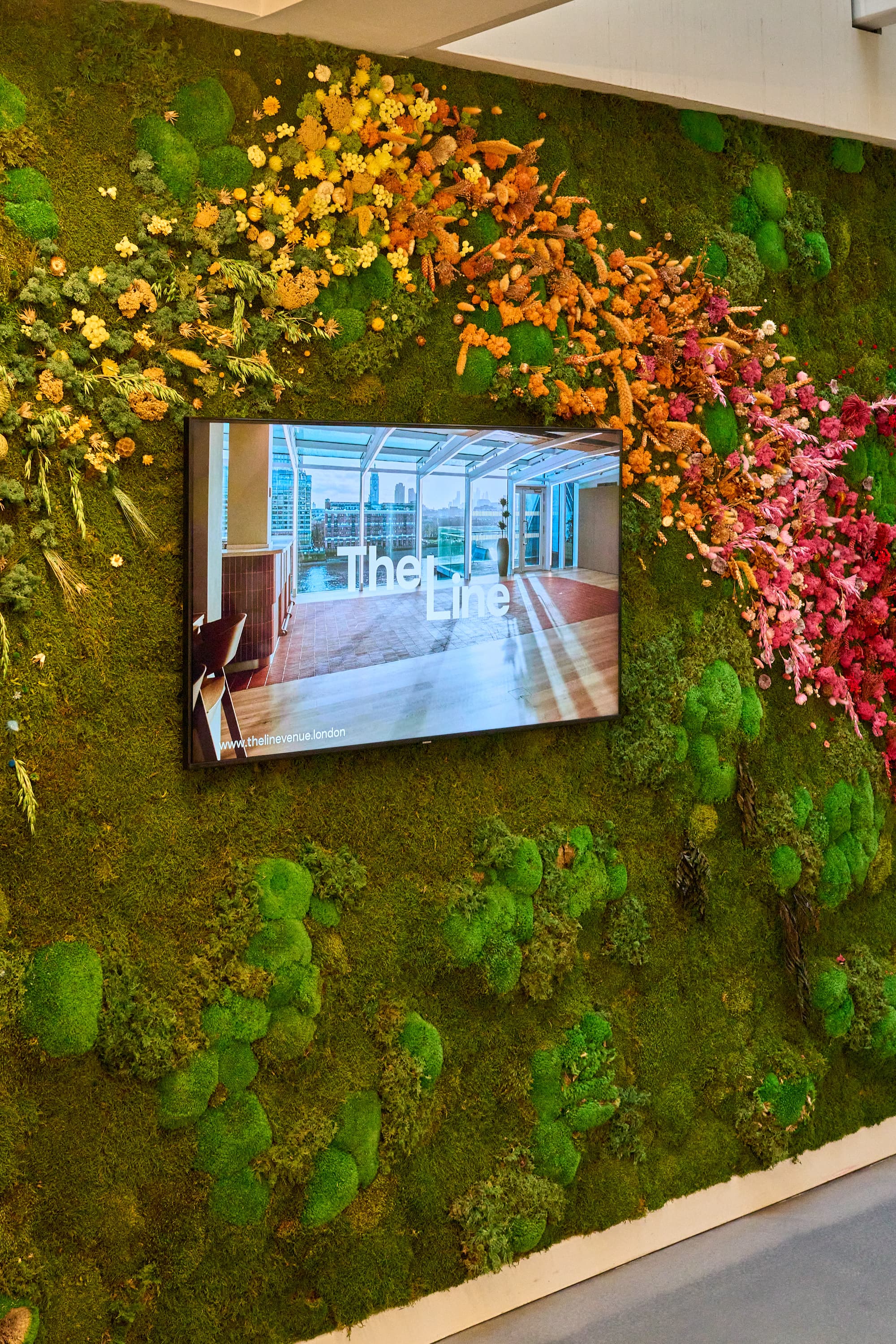 Digital venue showcase on a biophilic moss wall for corporate event and brand activation.
