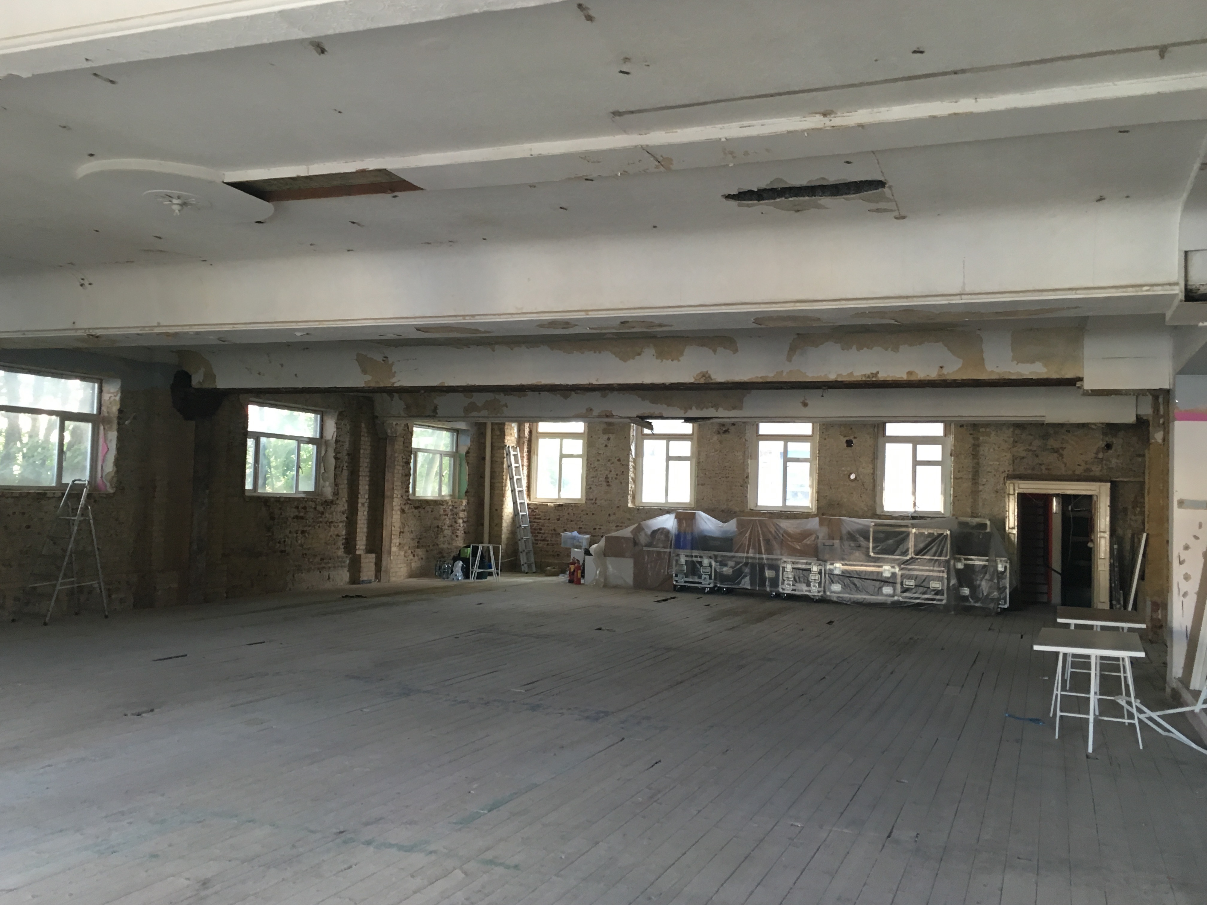 Spacious, unfinished event venue with exposed walls in 133 Rye Lane for creative meetings.
