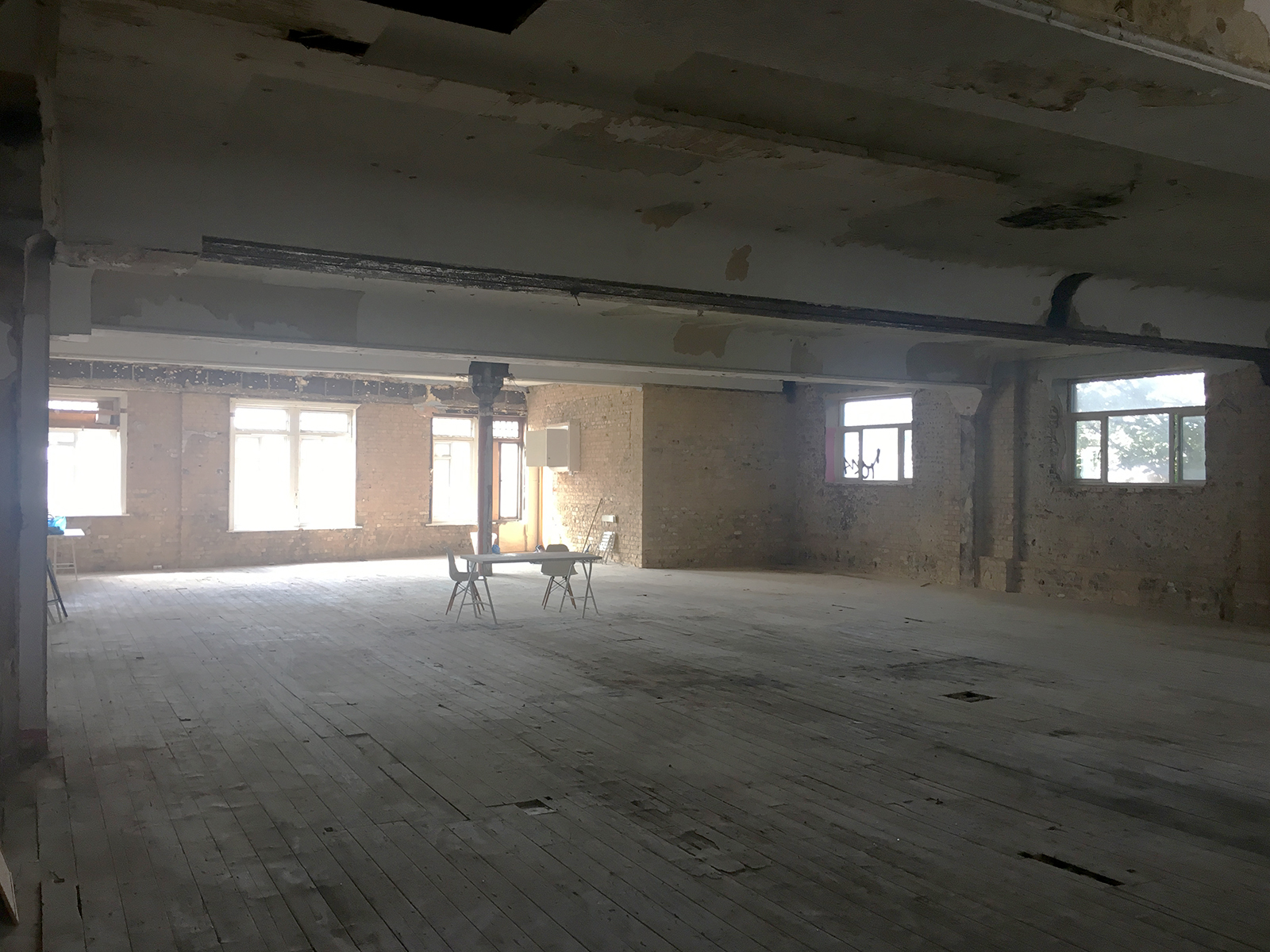 Spacious empty venue with exposed brick walls, ideal for workshops and events.