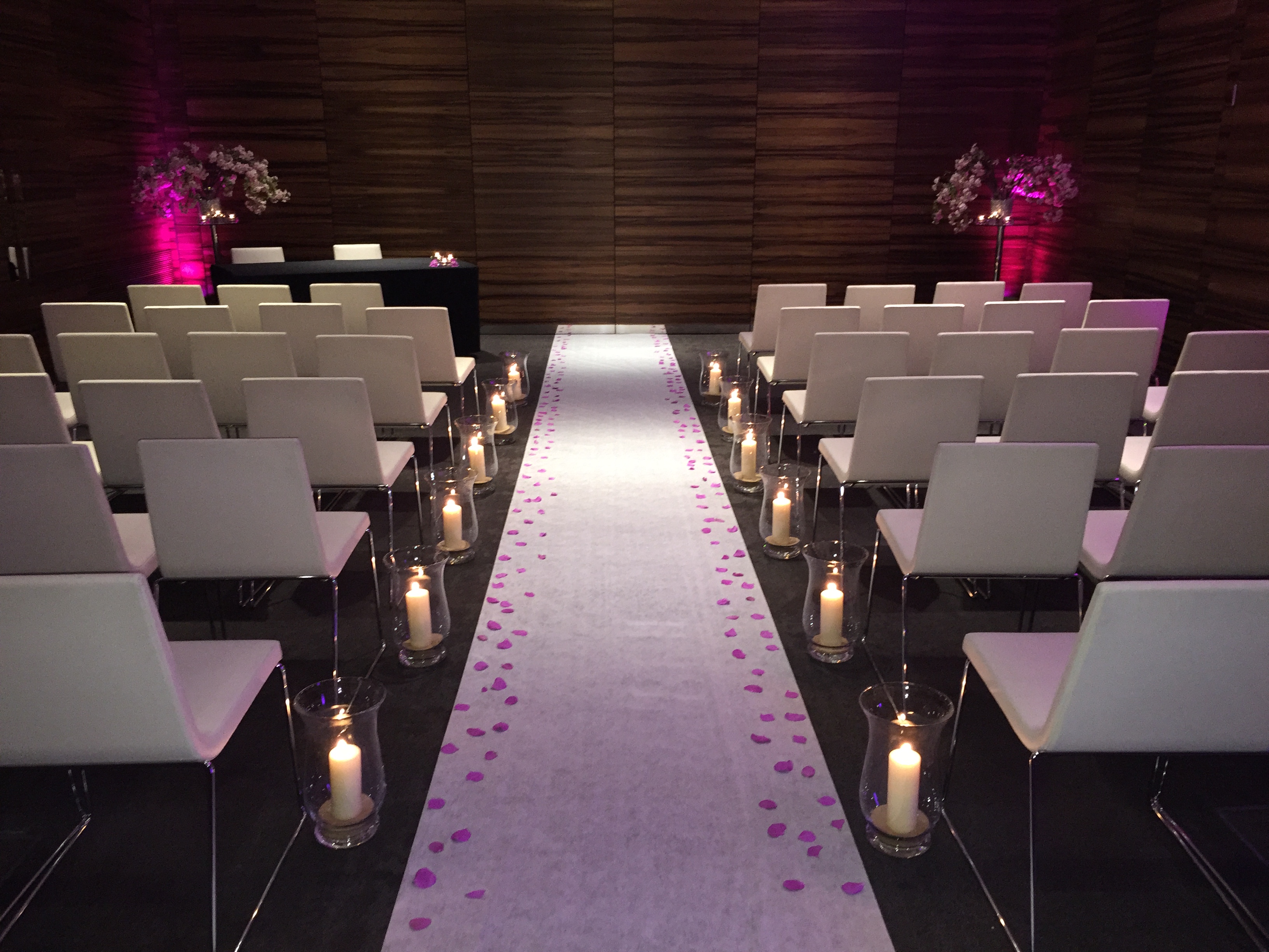 Intimate wedding ceremony space with white chairs and romantic pink lighting in ME London.