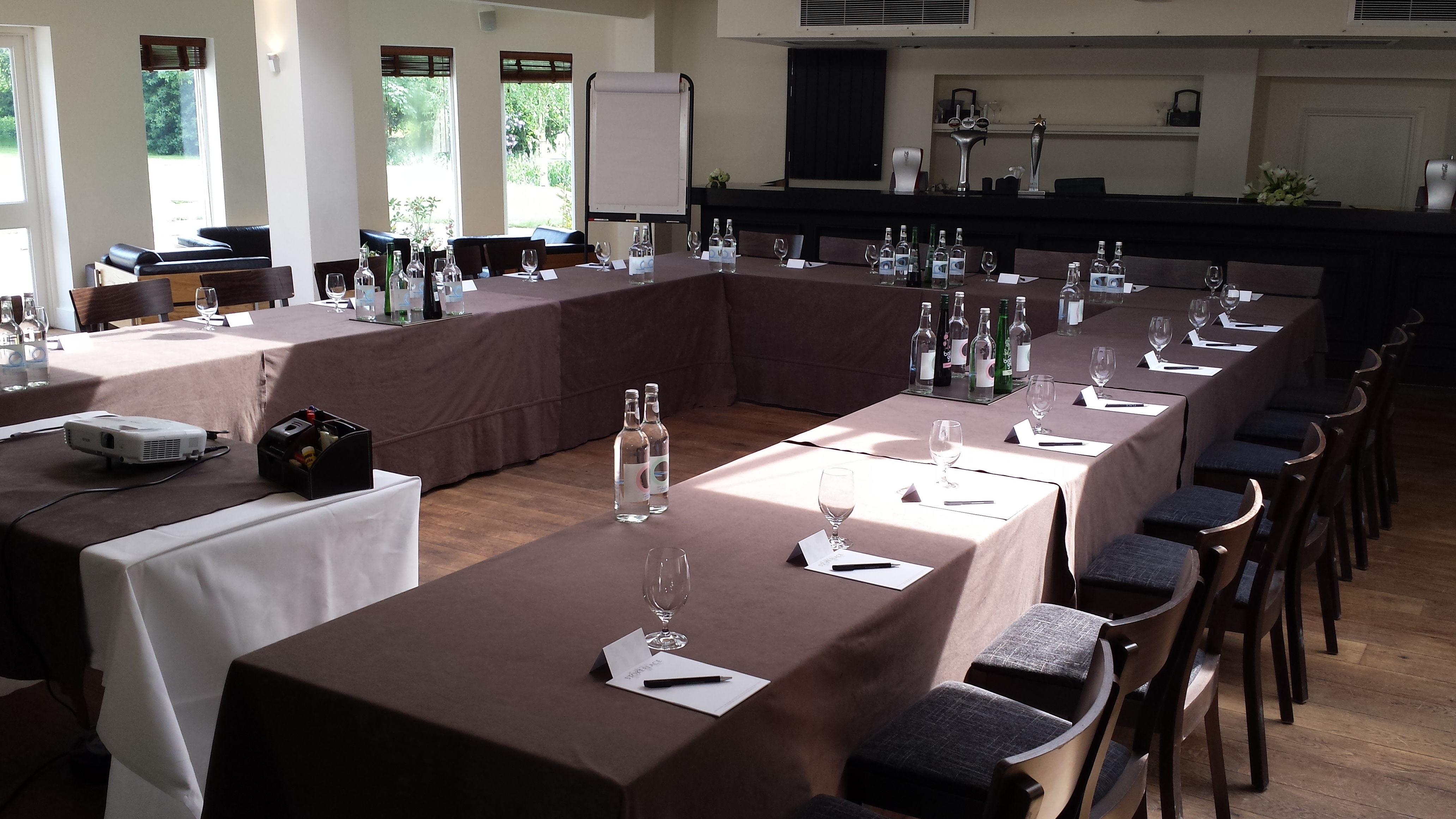 Lakeside meeting room with U-shaped tables, ideal for workshops and professional events.