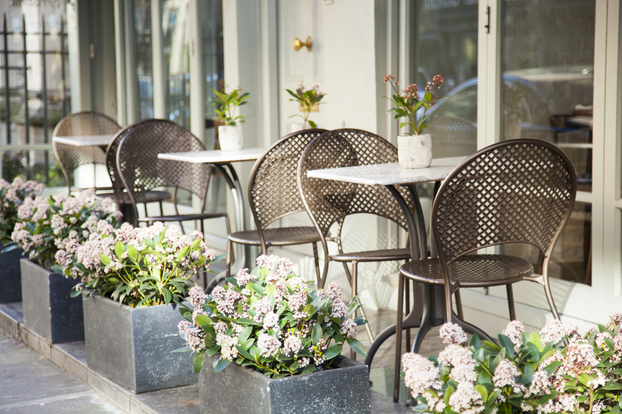 Outdoor café at Trishna for casual meetings and networking events with floral planters.
