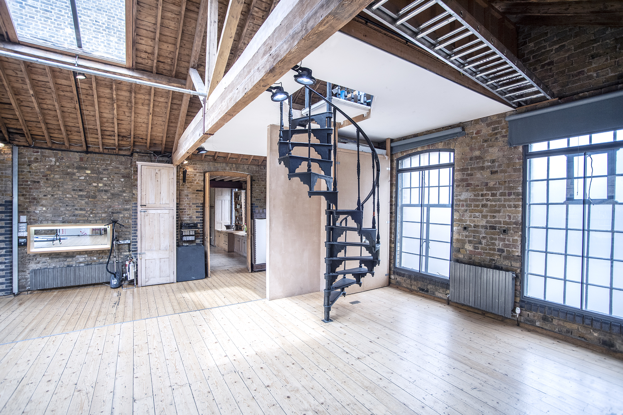 Versatile event space with exposed brick and spiral staircase for creative workshops.