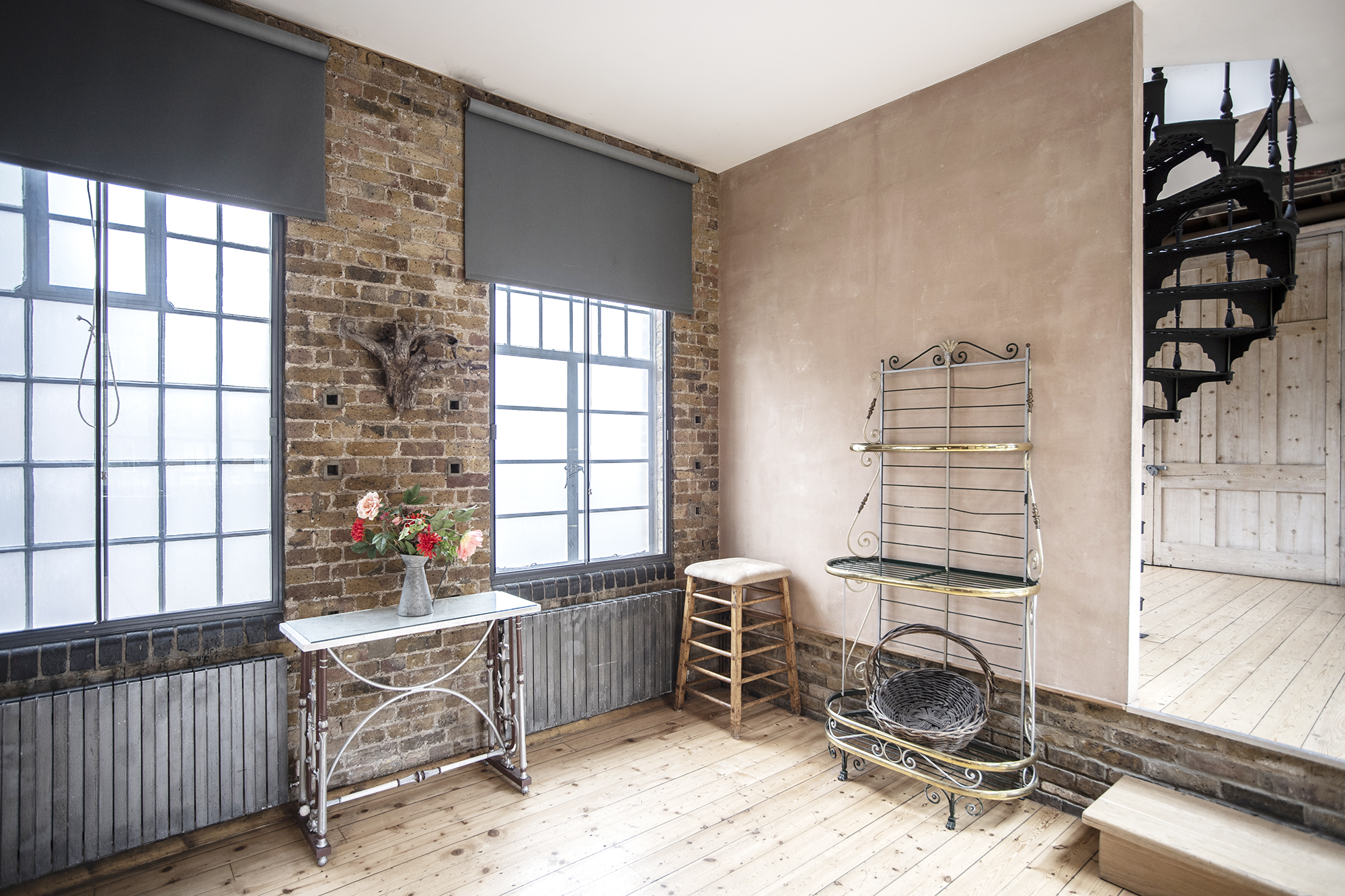 Versatile event space with exposed brick and spiral staircase for meetings and workshops.