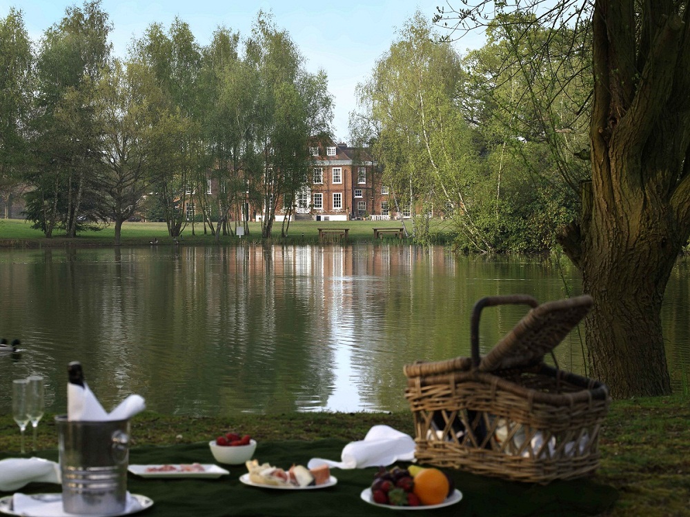 Serene outdoor corporate retreat at Stoke Place with lake and picnic setup.