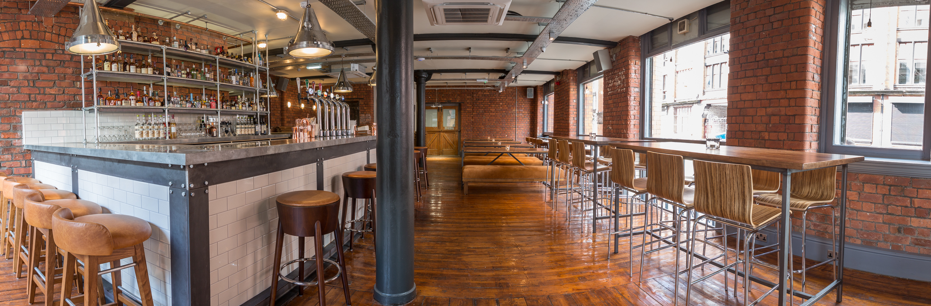 Versatile event space with modern bar, exposed brick, ideal for gatherings and networking.
