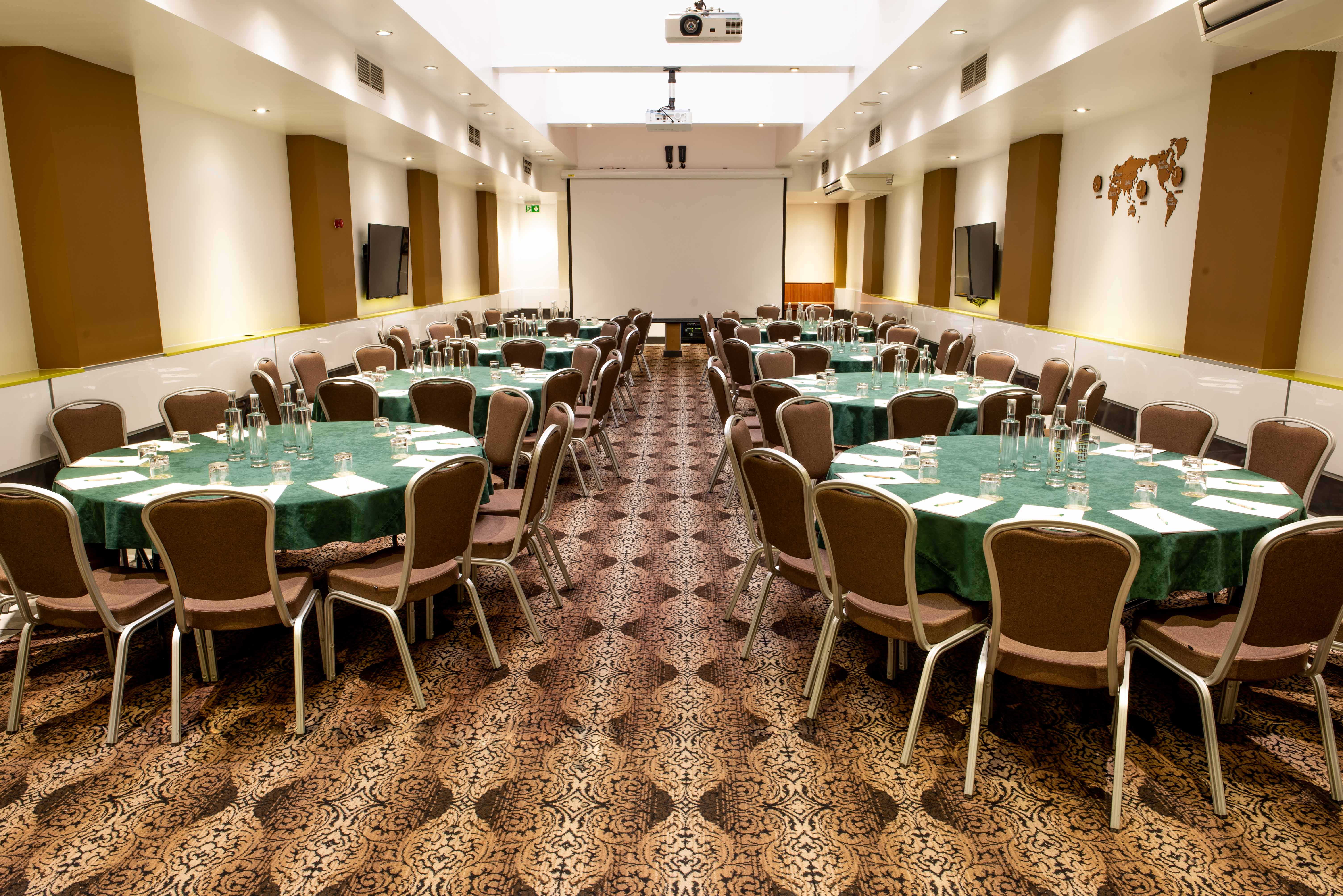Porter Hall at Wesley Euston Hotel, elegant conference space with green tables and AV setup.