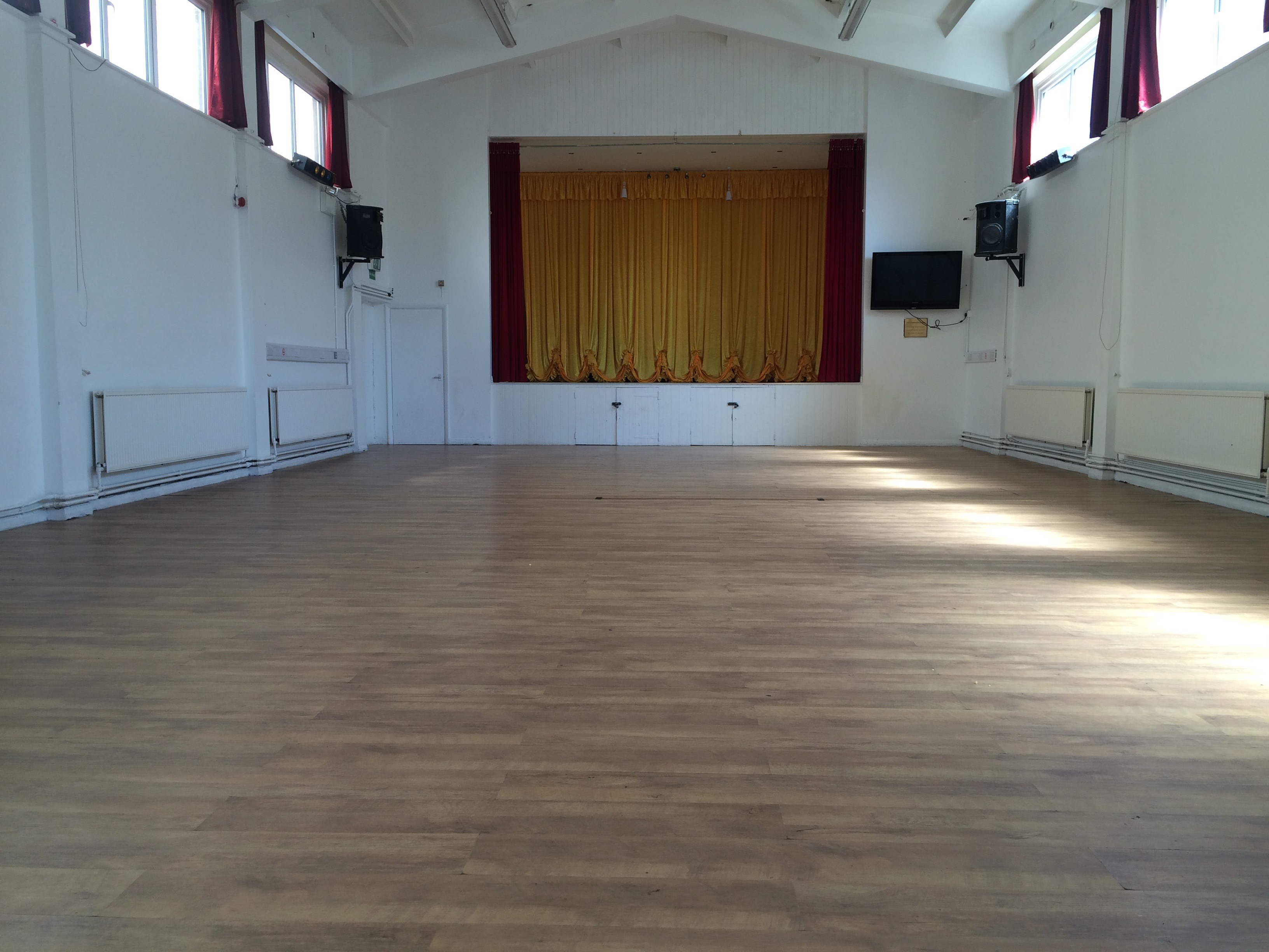 Spacious Main Hall at Centre 151 with golden stage curtain for events and workshops.
