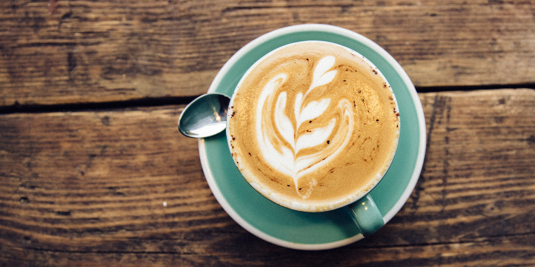 Intricate latte art in stylish cup on rustic table, perfect for networking events.