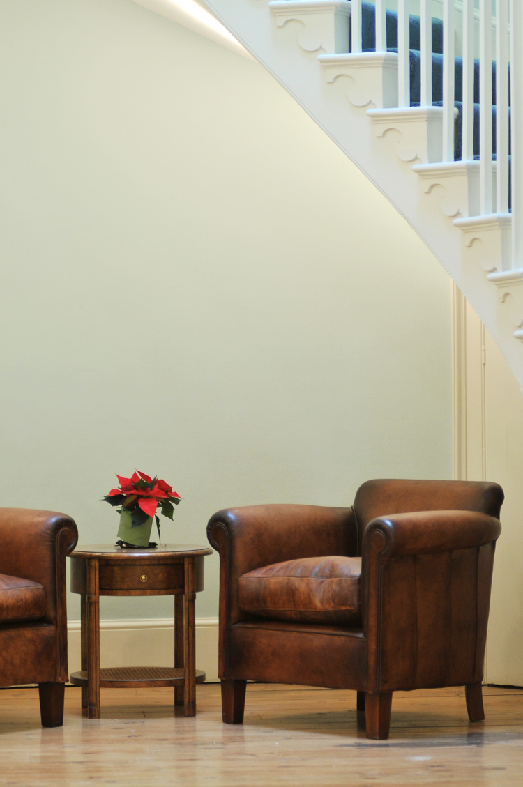 Cozy Church View Room with leather chairs and poinsettia for events and networking.