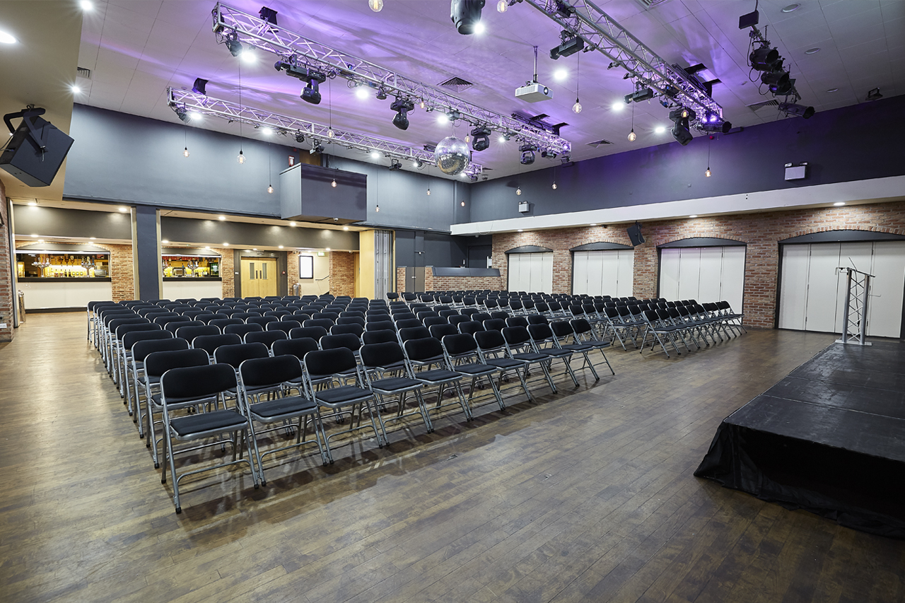 Versatile event space with black chairs, ideal for conferences and presentations.