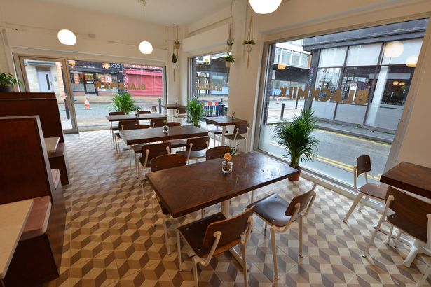 Bright Black Milk Cafe with wooden tables, perfect for casual meetings and small events.