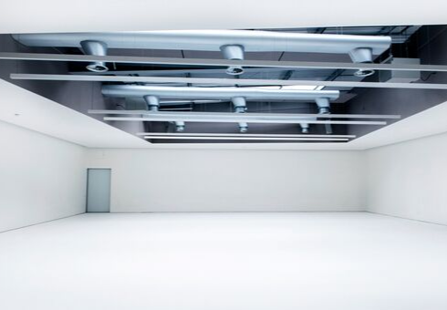 Minimalist event space with high ceiling and natural light for corporate meetings or workshops.