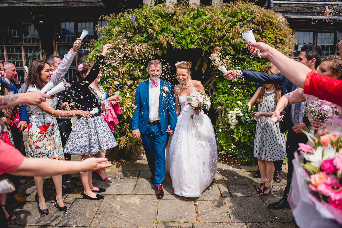 Joyful wedding celebration in Great Hall, Blakesley Hall with confetti and floral decor.