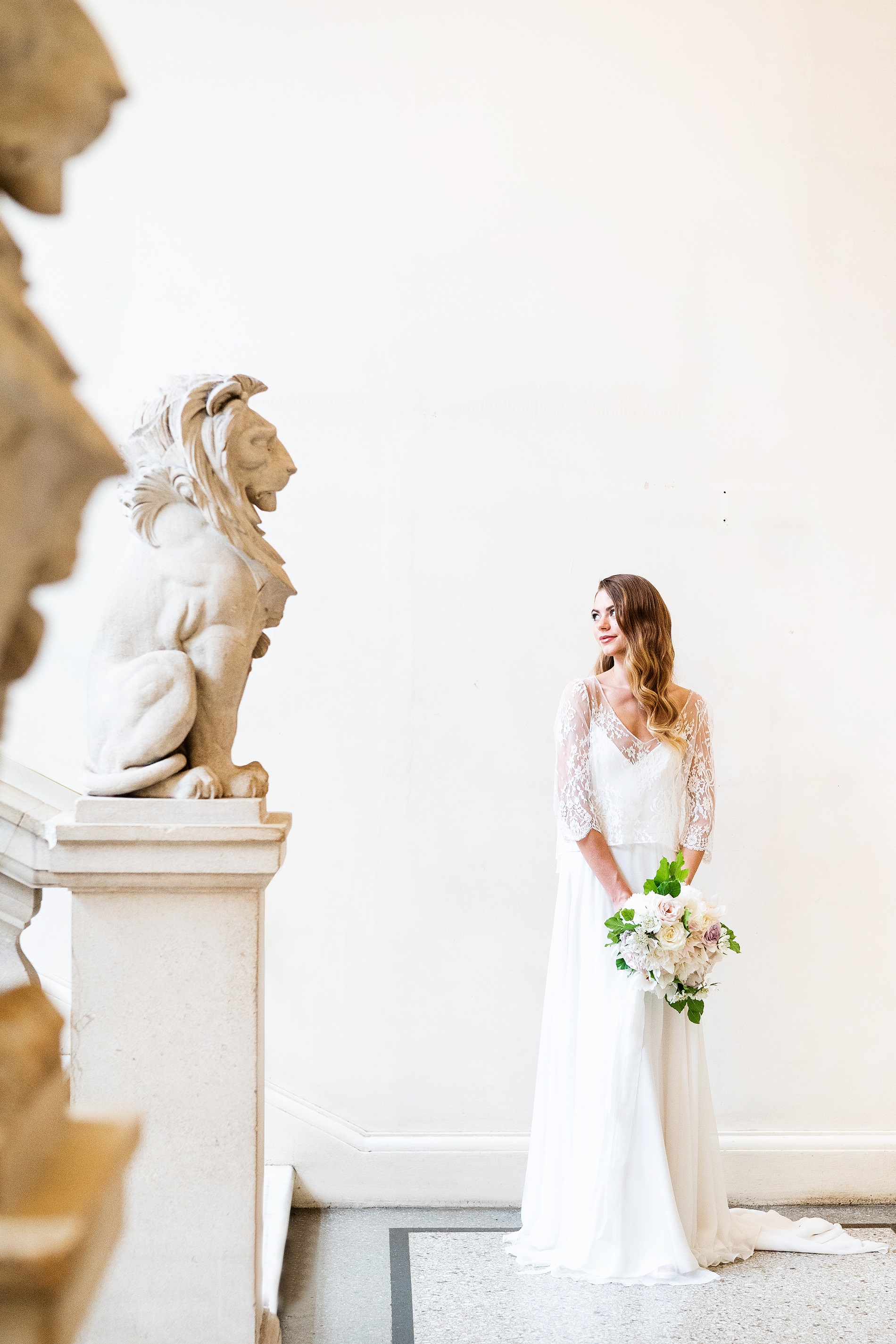 Bride beside lion statue at Bristol Museum, ideal for weddings and upscale events.