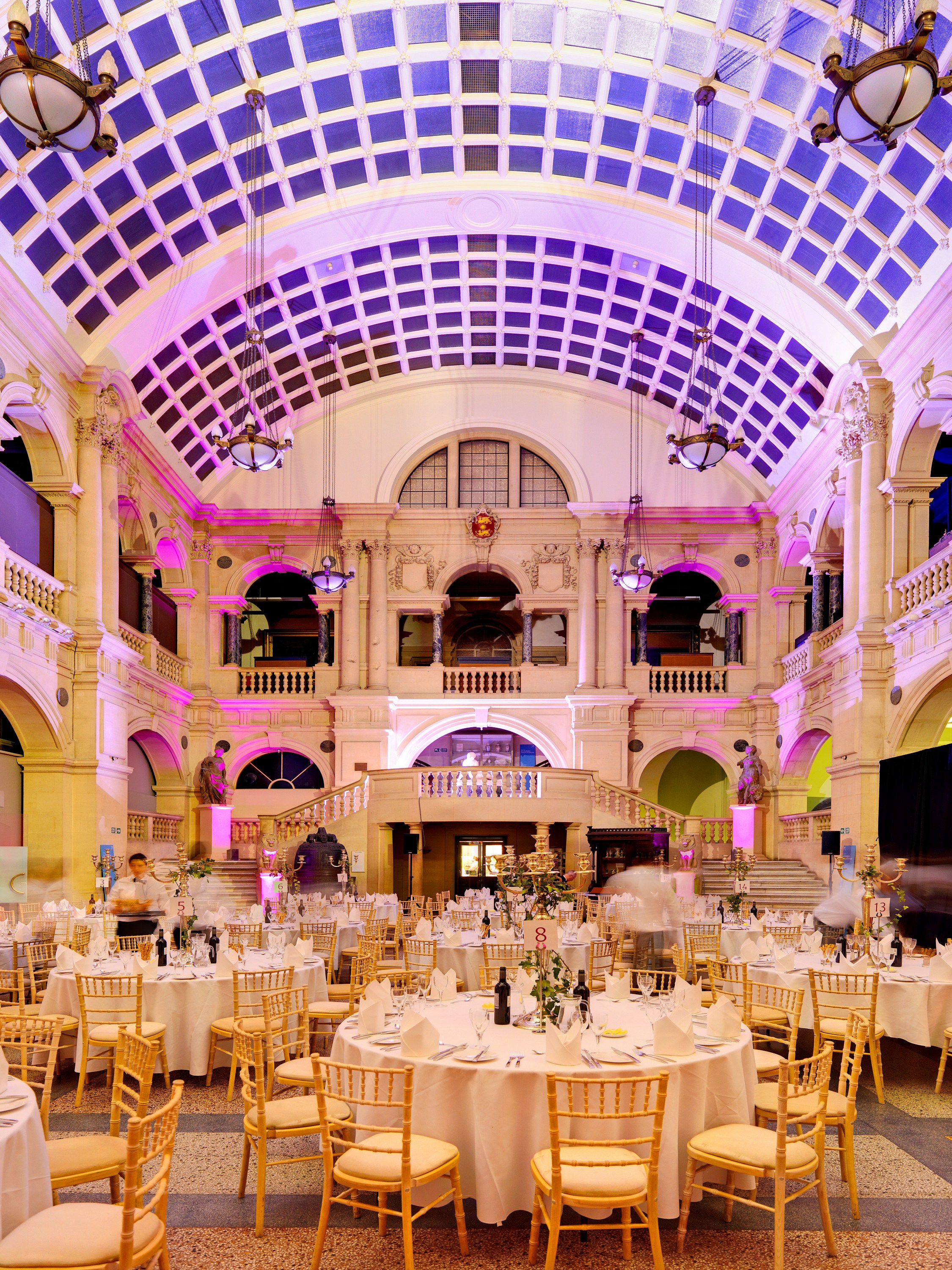 Elegant event space in Bristol Museum with grand architecture and soft purple lighting.