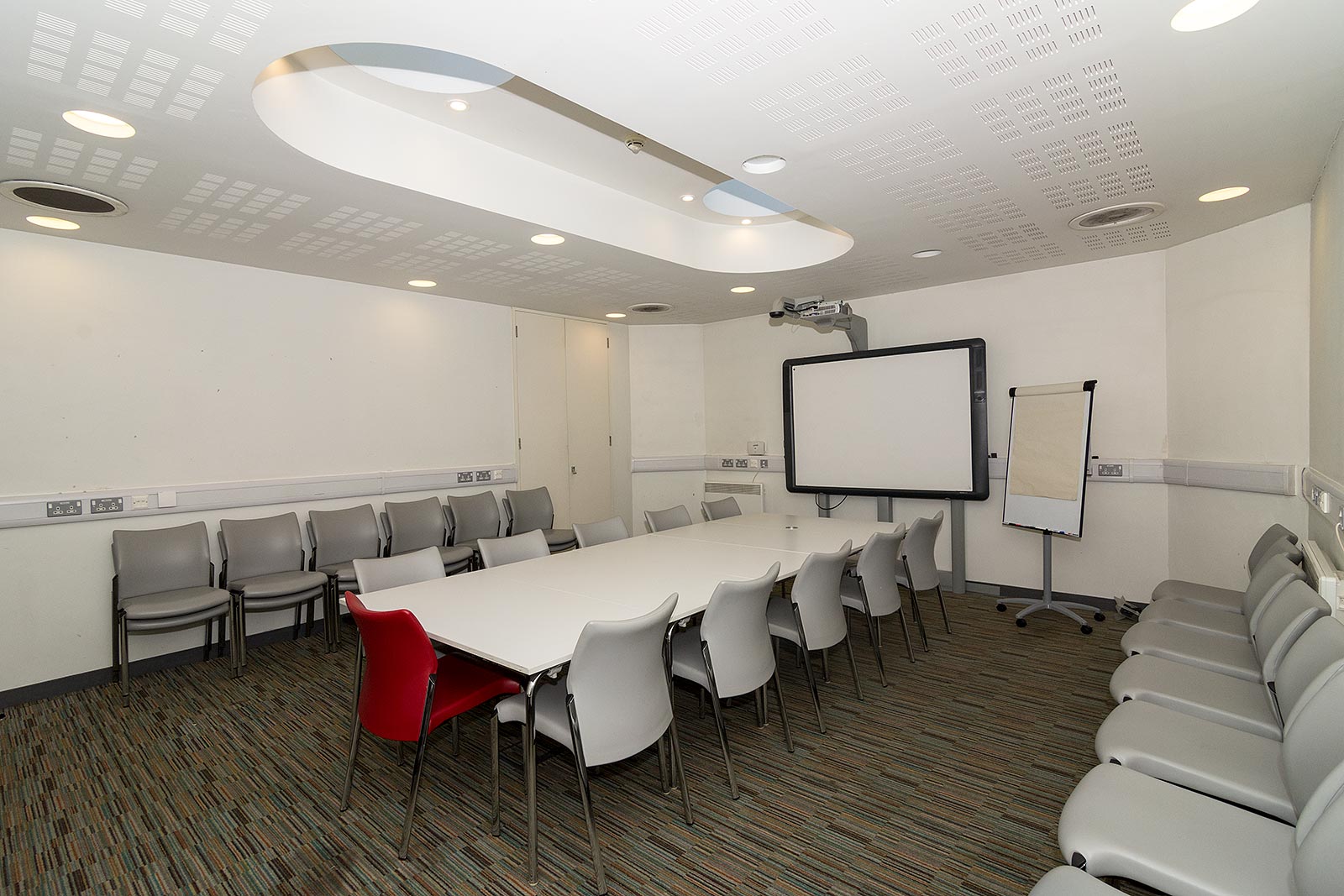 Modern meeting room with large table, projector, and ergonomic chairs at John Harvard Library.