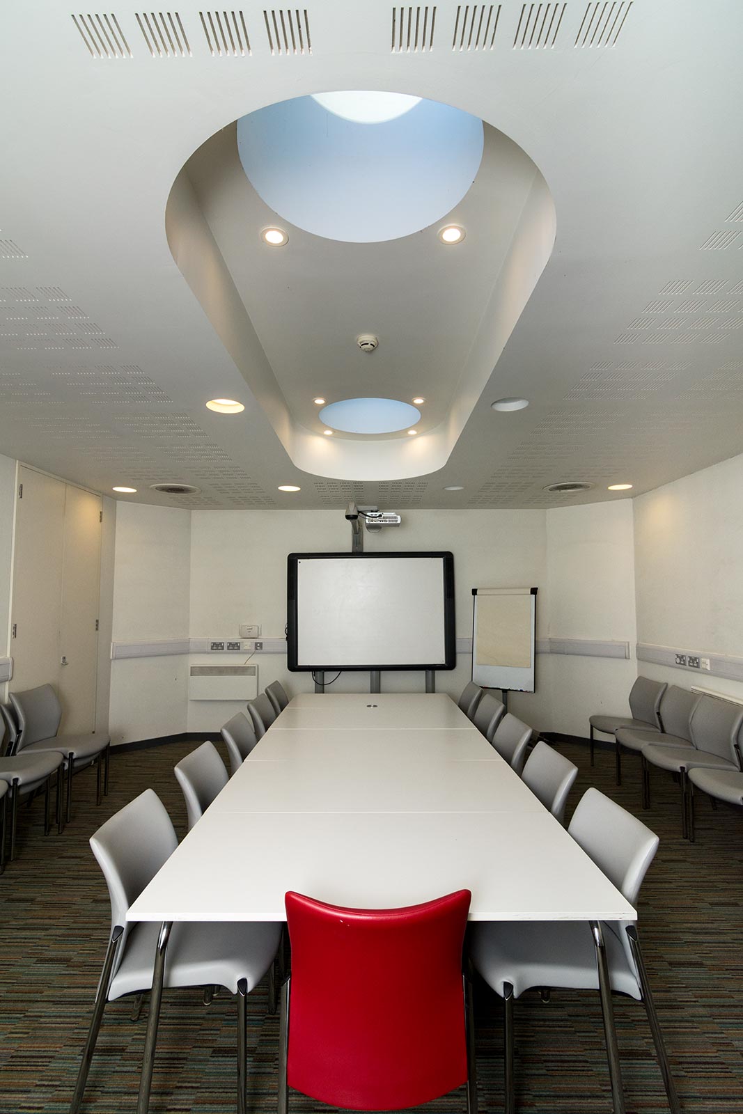 Modern meeting room in John Harvard Library with skylight, ideal for presentations and collaboration.