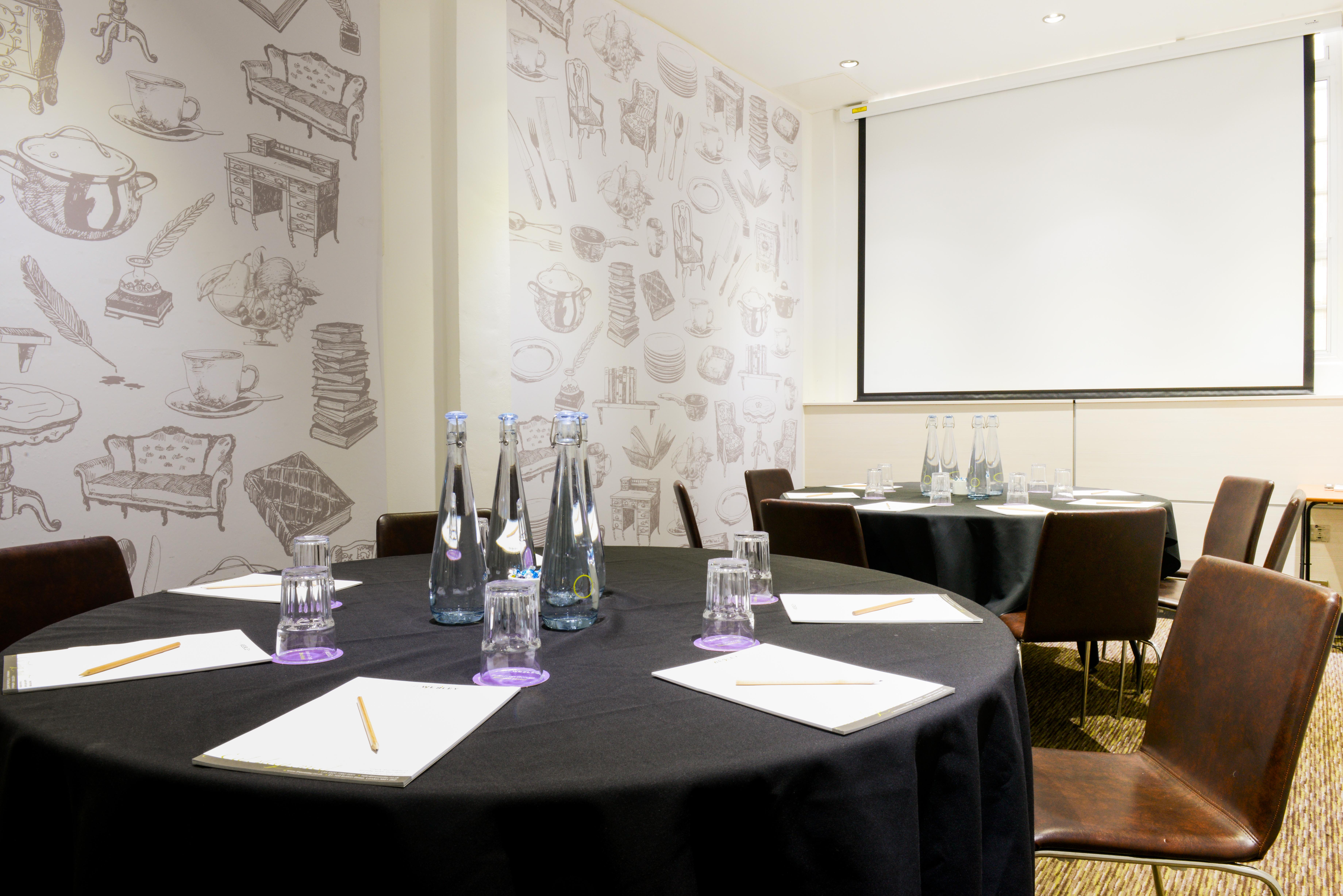 Meeting room at The Wesley Euston Hotel with round tables, ideal for conferences and events.