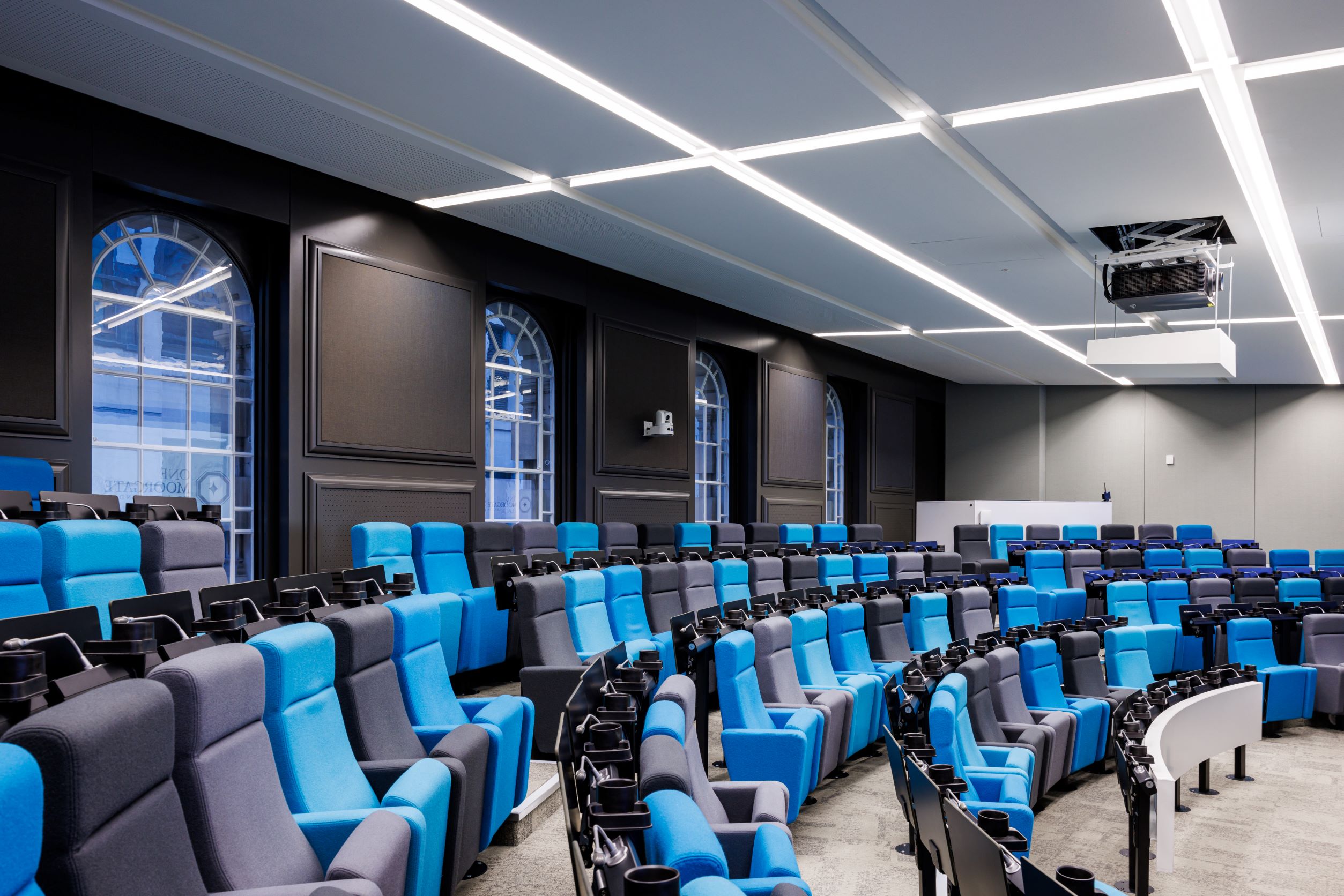 Modern auditorium with tiered blue seating, ideal for meetings and events.