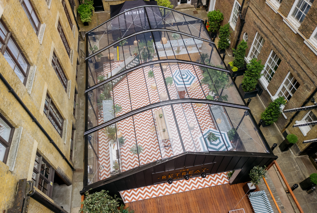 Stylish outdoor summer party at The Retreat with glass roof and vibrant greenery.