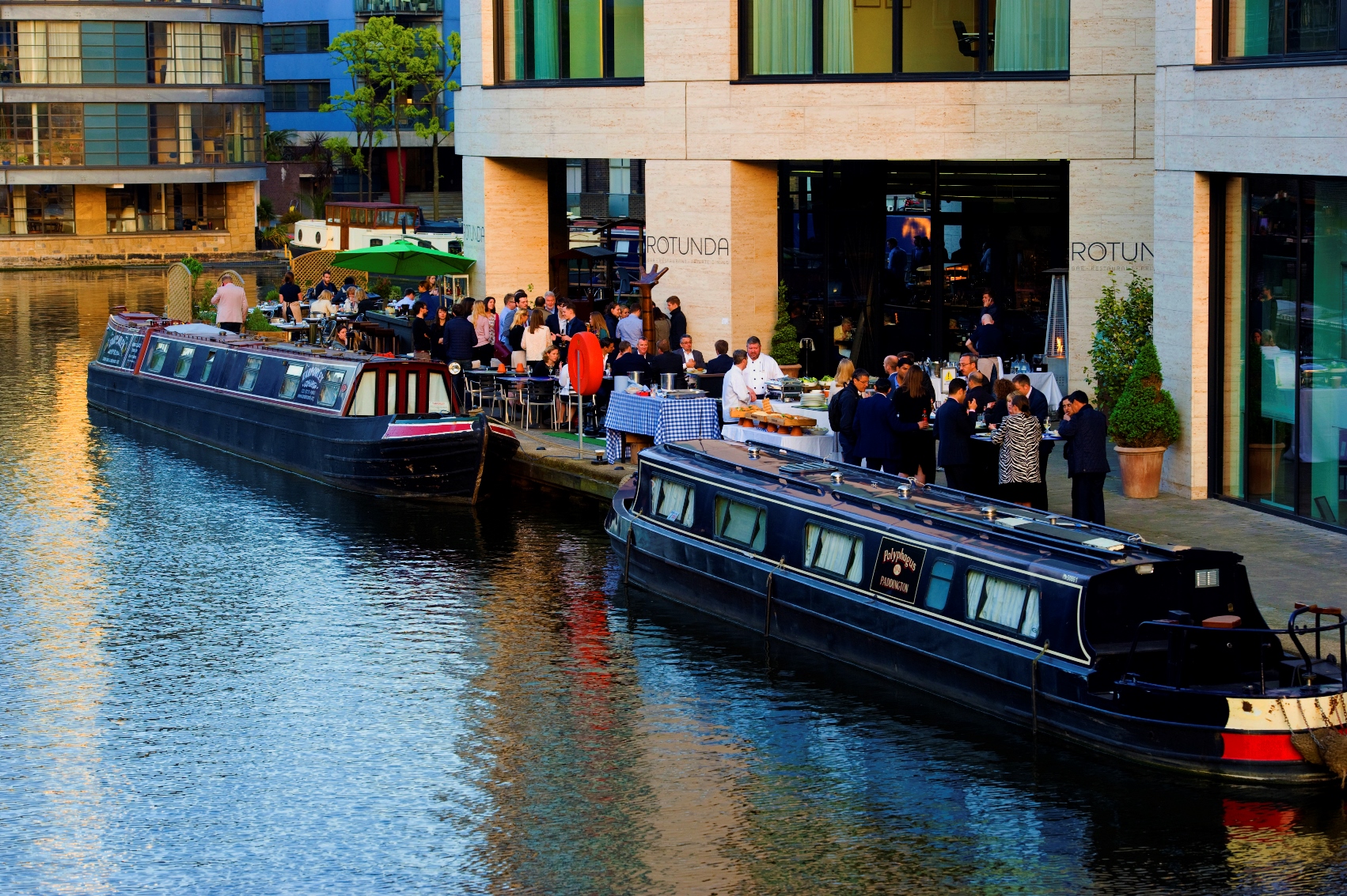 Vibrant outdoor networking event at Rotunda Bar with riverside views and elegant catering.