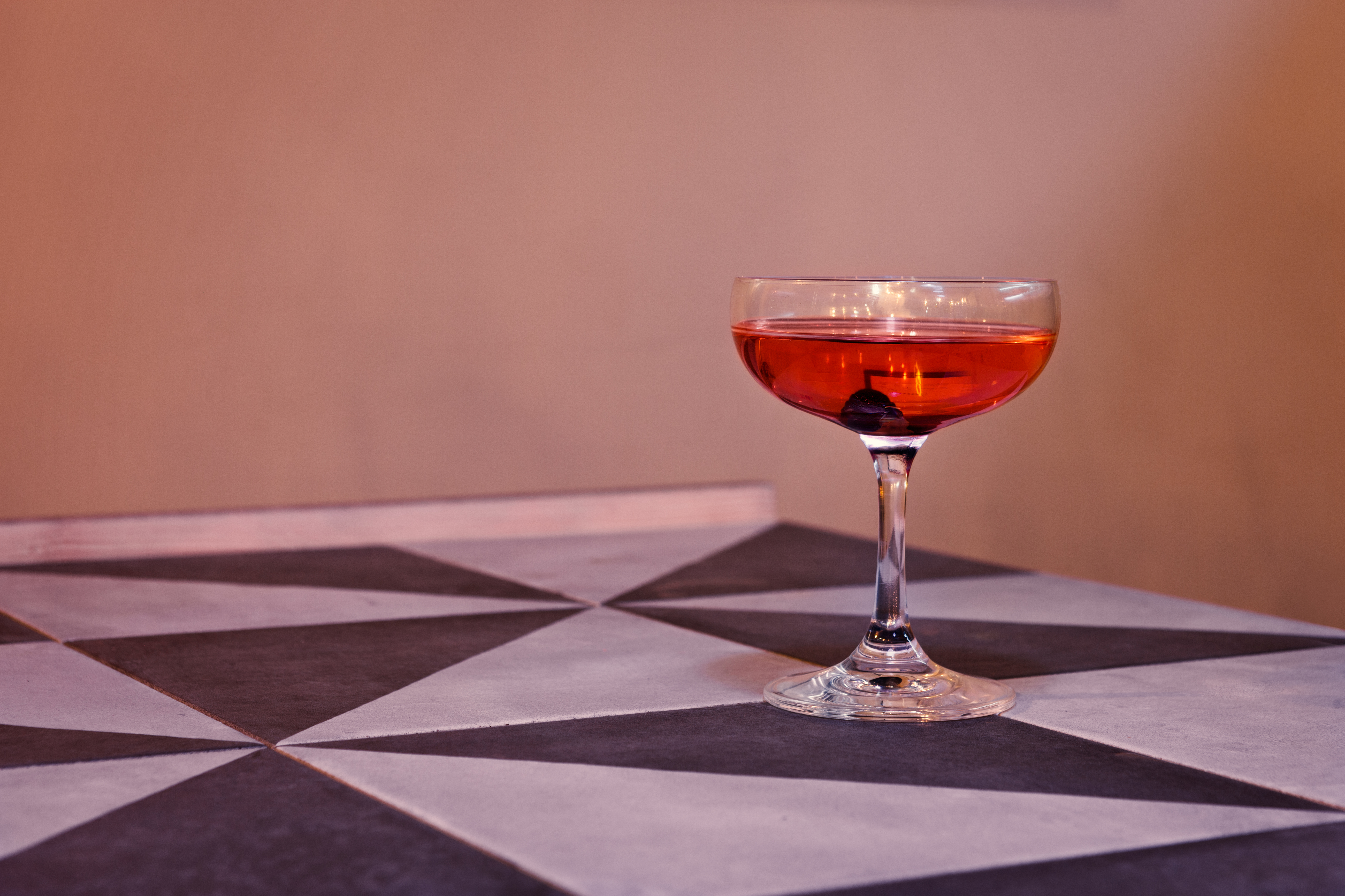 Elegant cocktail in coupe glass at upscale cafe bar, perfect for networking events.