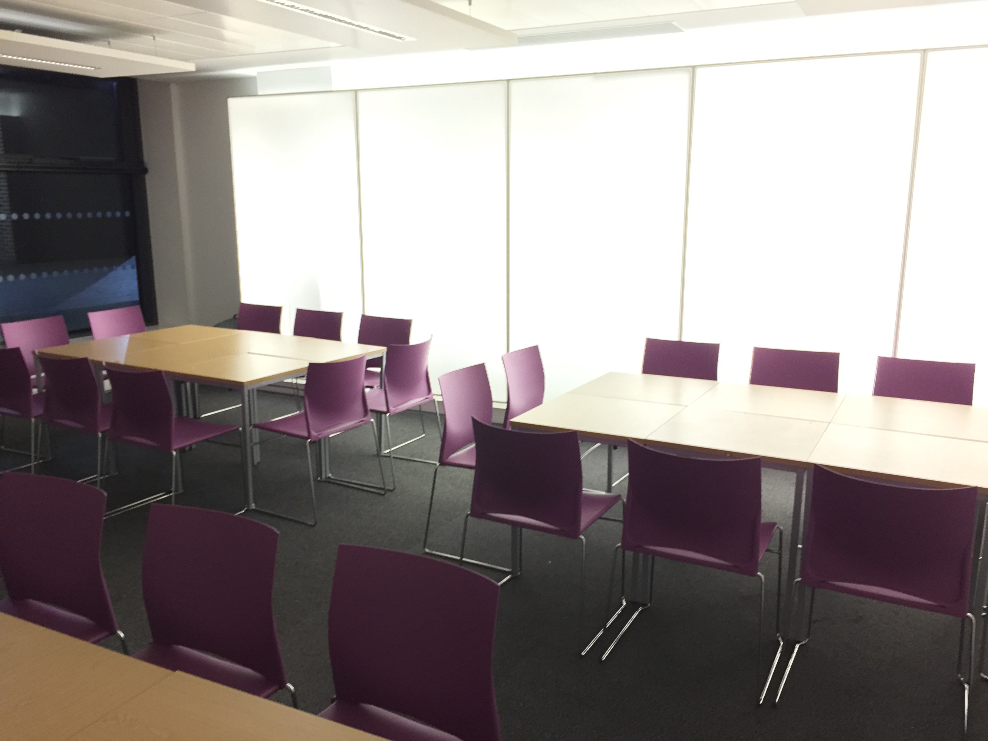 Modern meeting room at Queen Mary University with purple chairs, ideal for events.