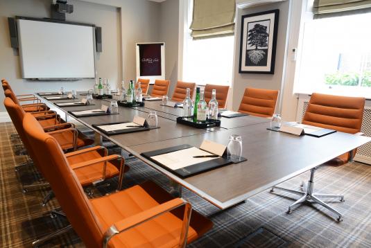 Cedar Room at Oatlands Park Hotel, modern meeting space with orange chairs and natural light.