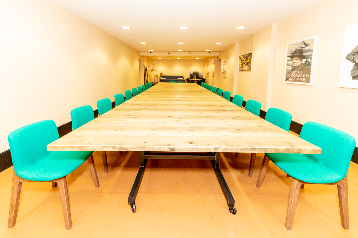 Spacious Churchill War Rooms meeting room with wooden table and teal chairs for workshops.