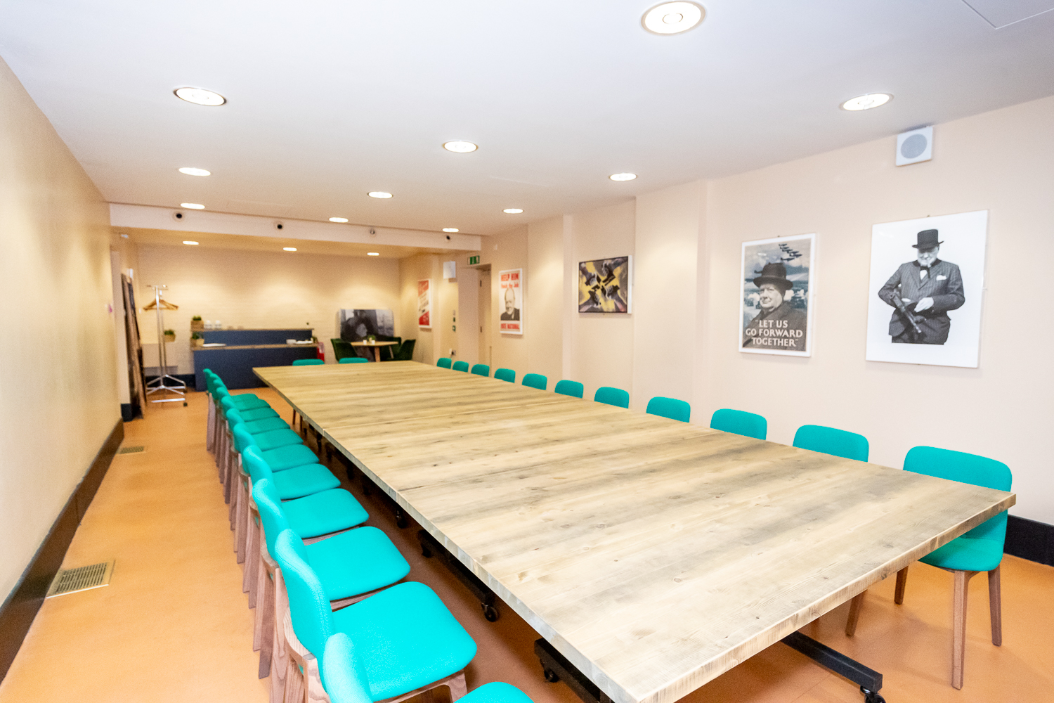 Spacious Churchill War Rooms meeting room with wooden table and teal chairs for workshops.