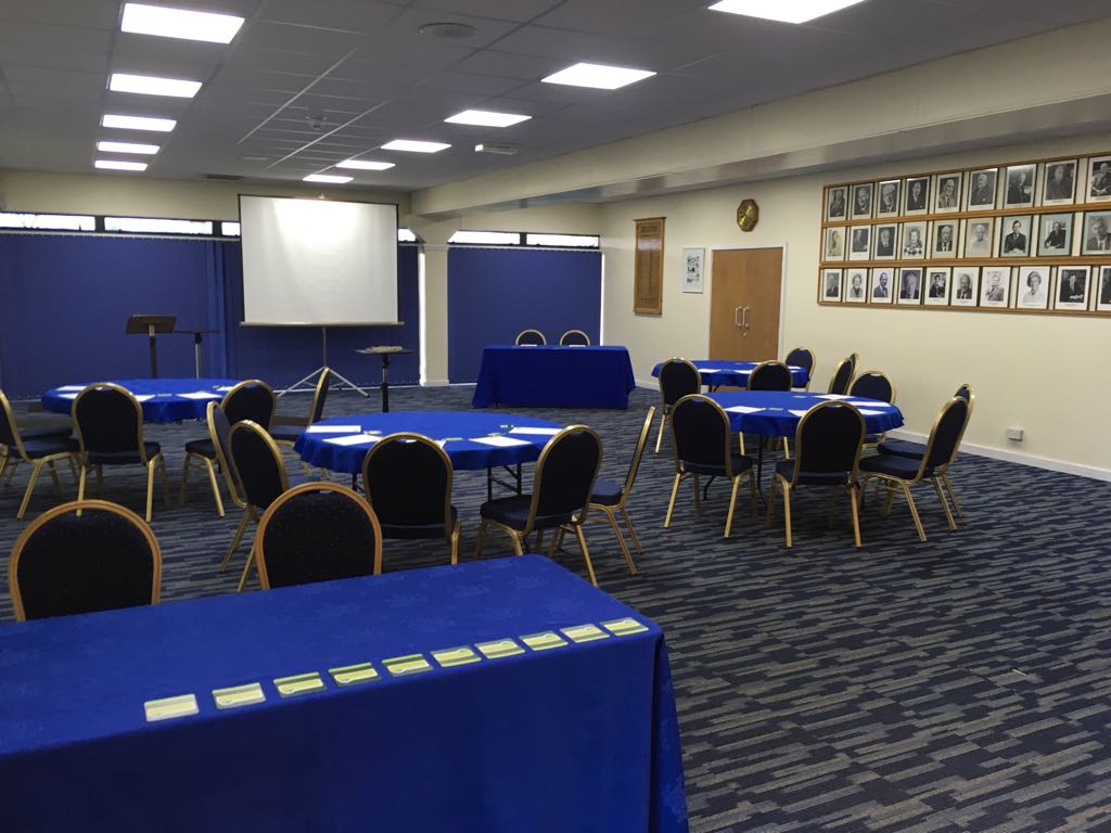 Kleinwort Room: versatile meeting space with round tables and blue tablecloths for events.