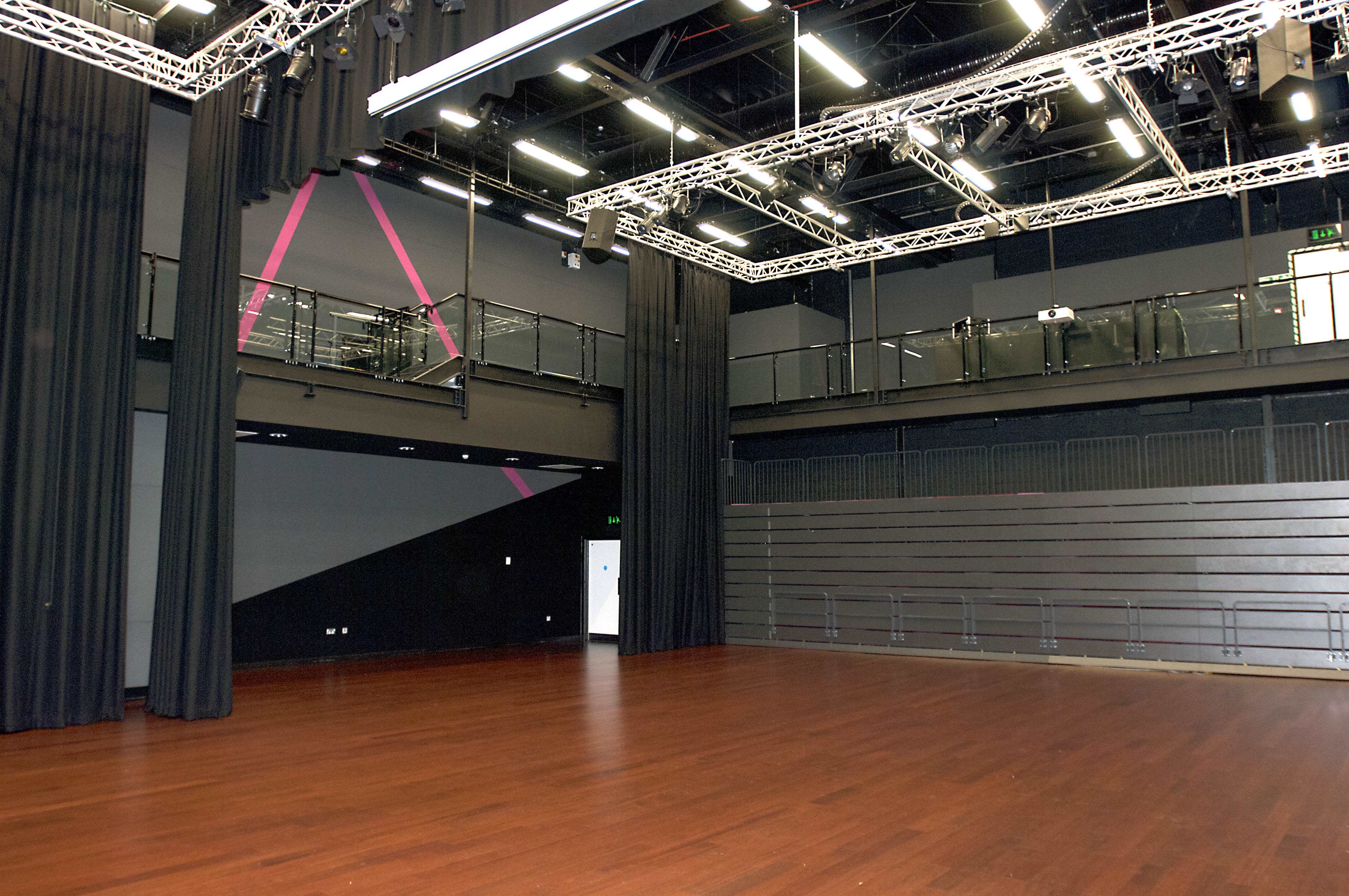 Versatile auditorium with wooden floor, ideal for conferences and performances.