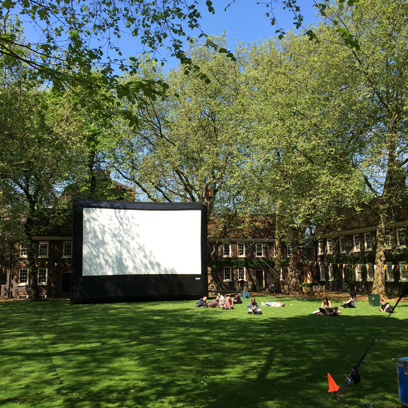 Outdoor event setup with inflatable screen in lush courtyard for film screenings.