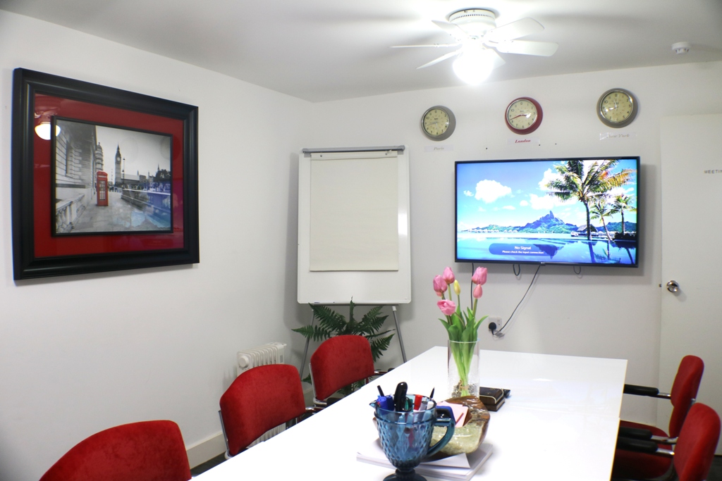 Modern meeting room with large white table and red chairs for professional gatherings.