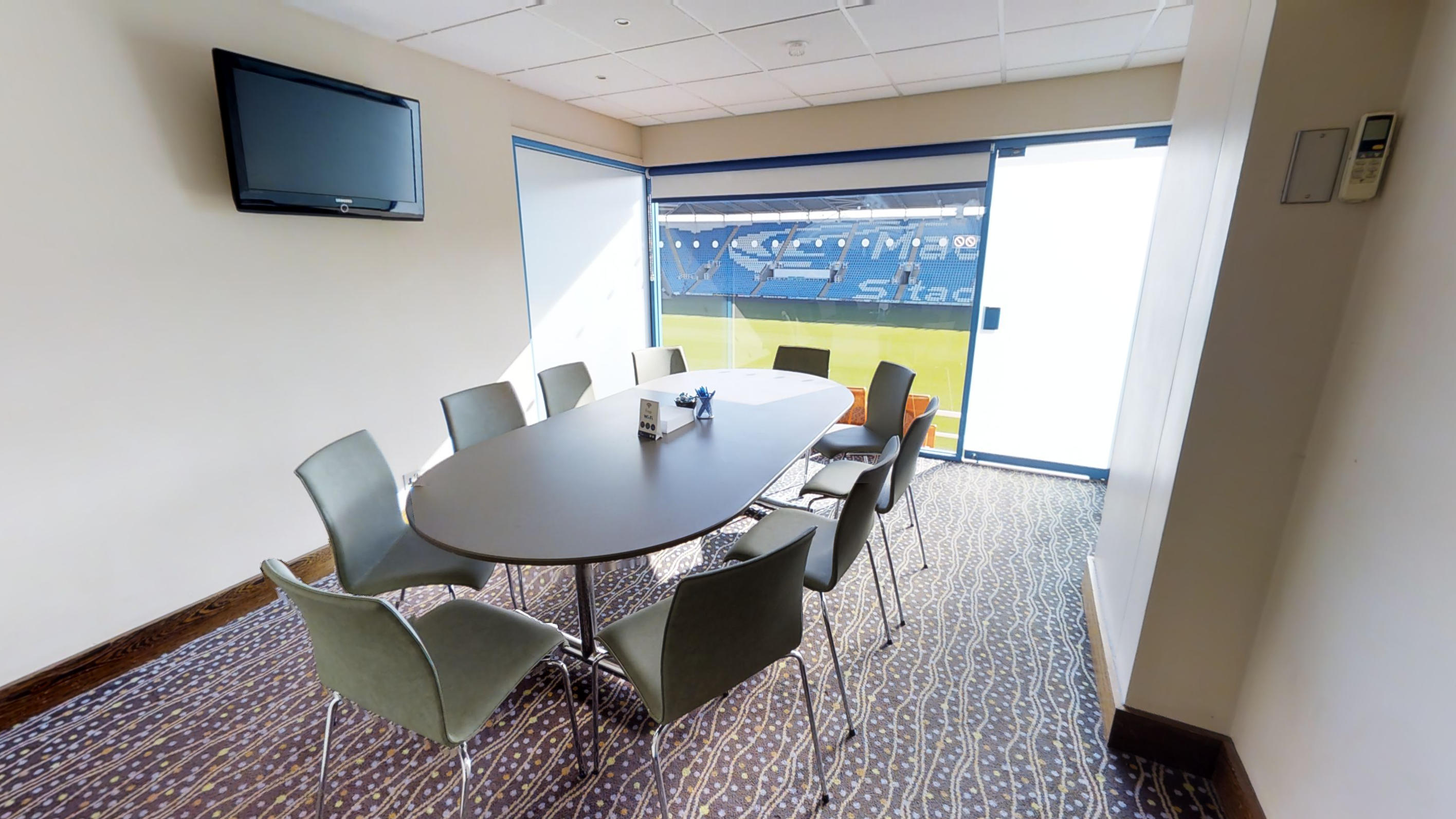 Modern executive meeting room with oval table and large windows at Reading FC Conference.