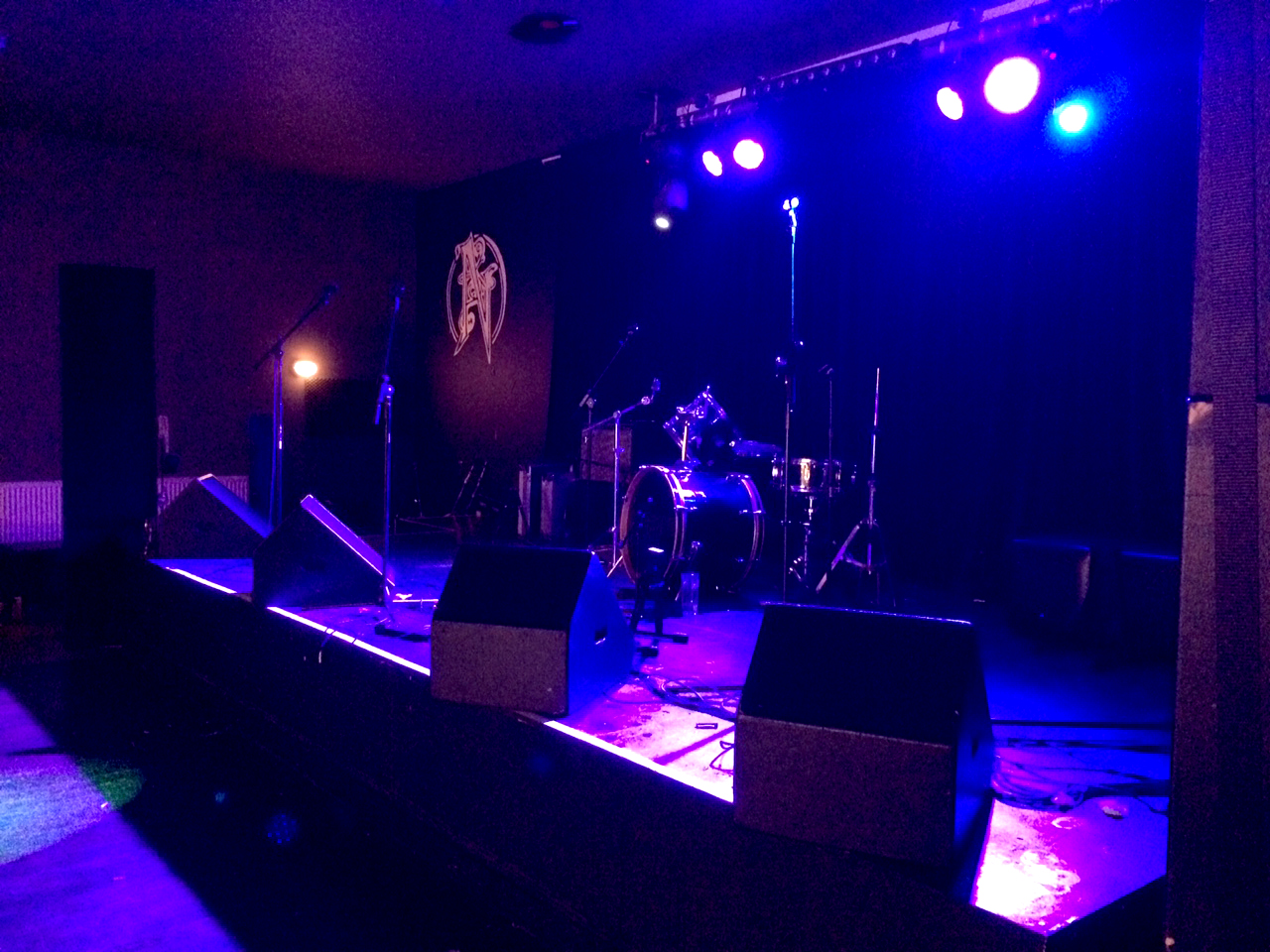 Stage setup for a live concert in Nambucca with blue lighting and drum kit.