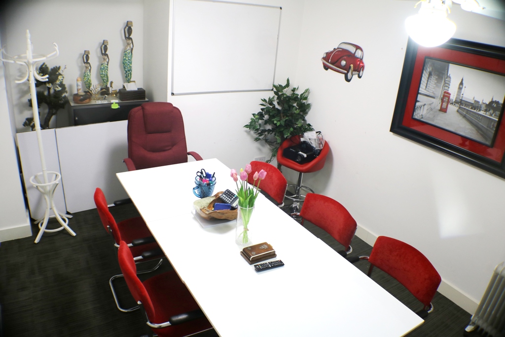 Modern meeting room with white table and red chairs, perfect for creative brainstorming sessions.