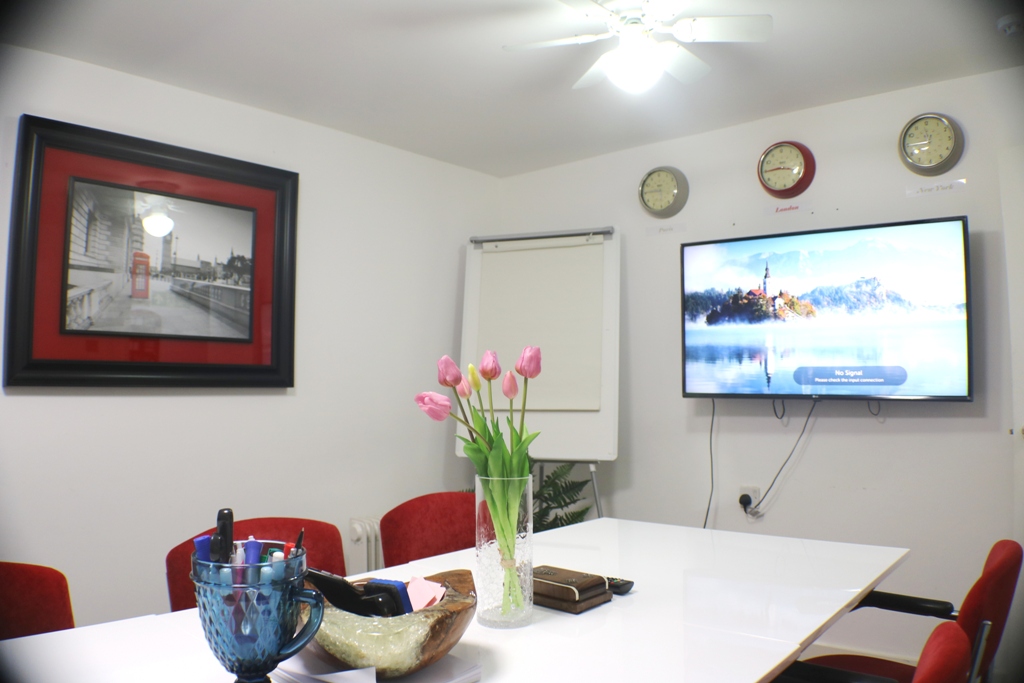 Modern meeting room with large table and red chairs, perfect for corporate events.