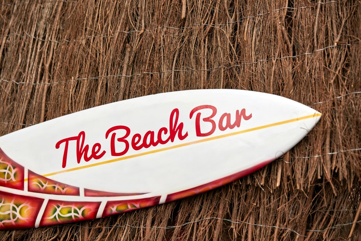 Surfboard sign at The Beach Bar, ideal for summer parties and beach-themed events.