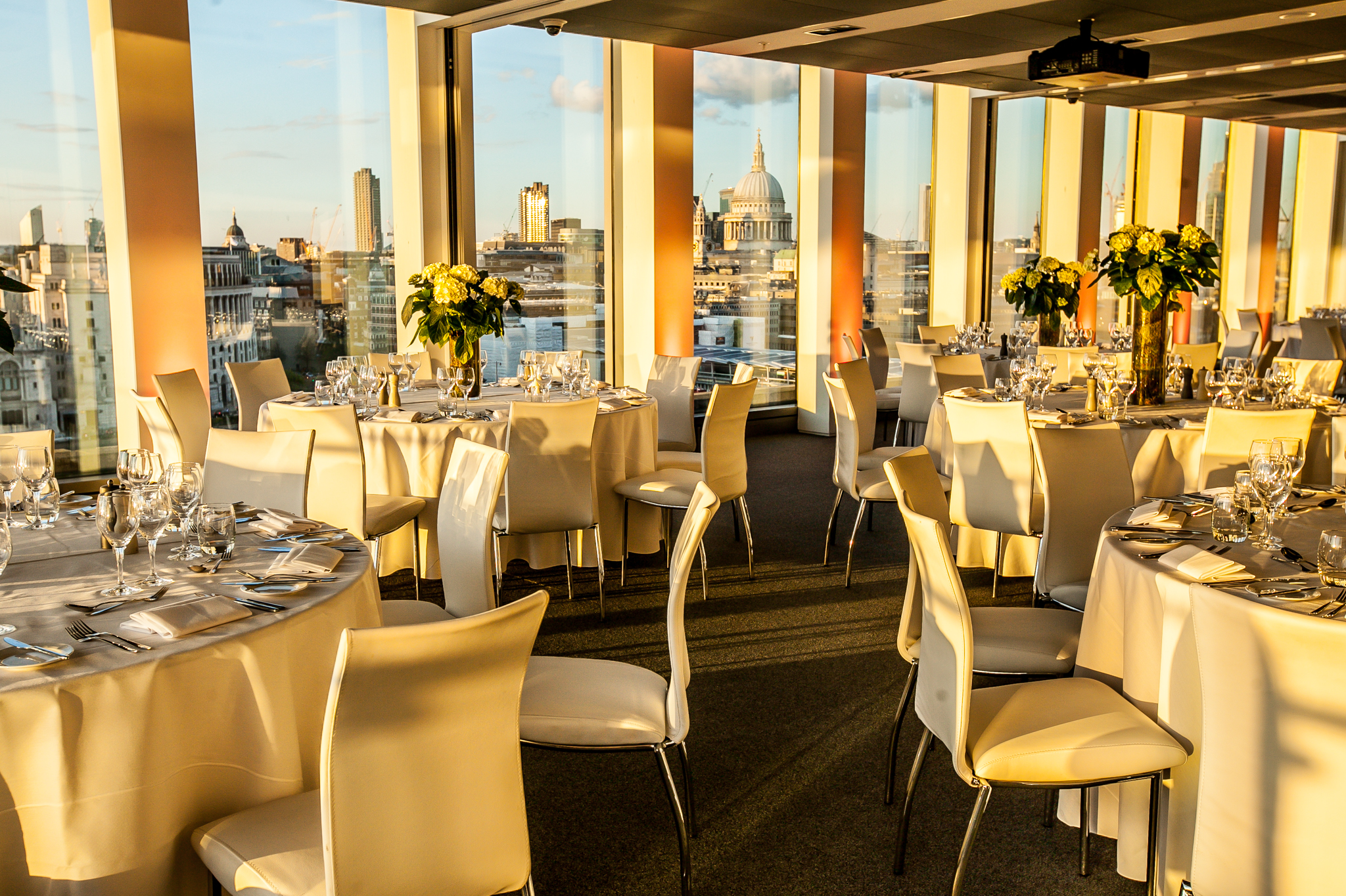 Elegant event space with round tables and city views, ideal for corporate gatherings.