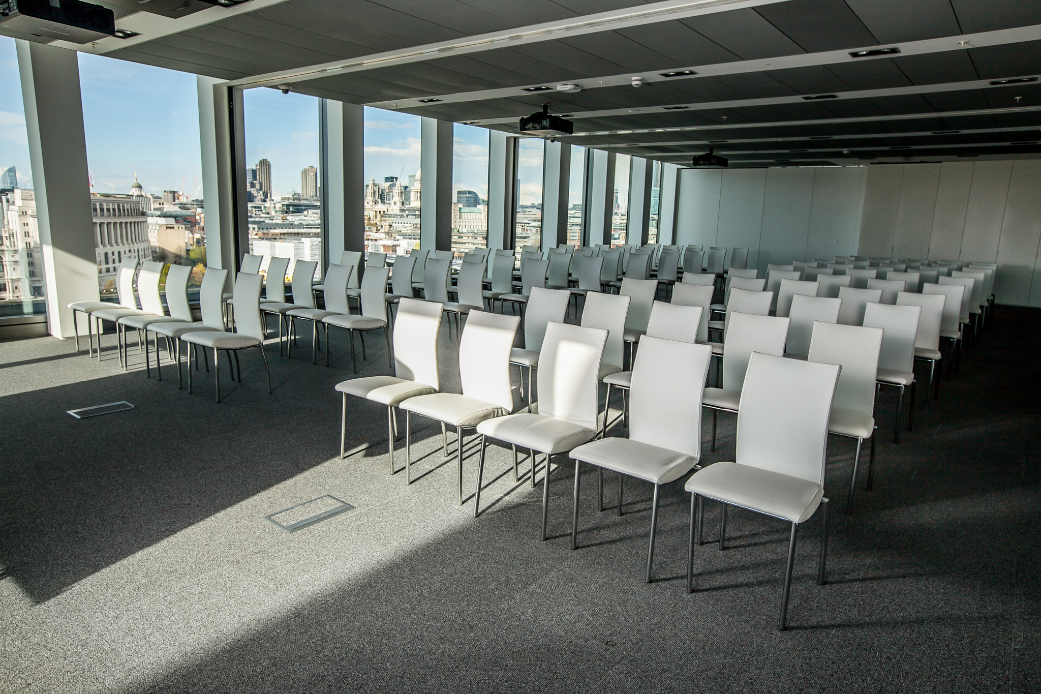Modern event space with white chairs and city view for presentations or seminars.