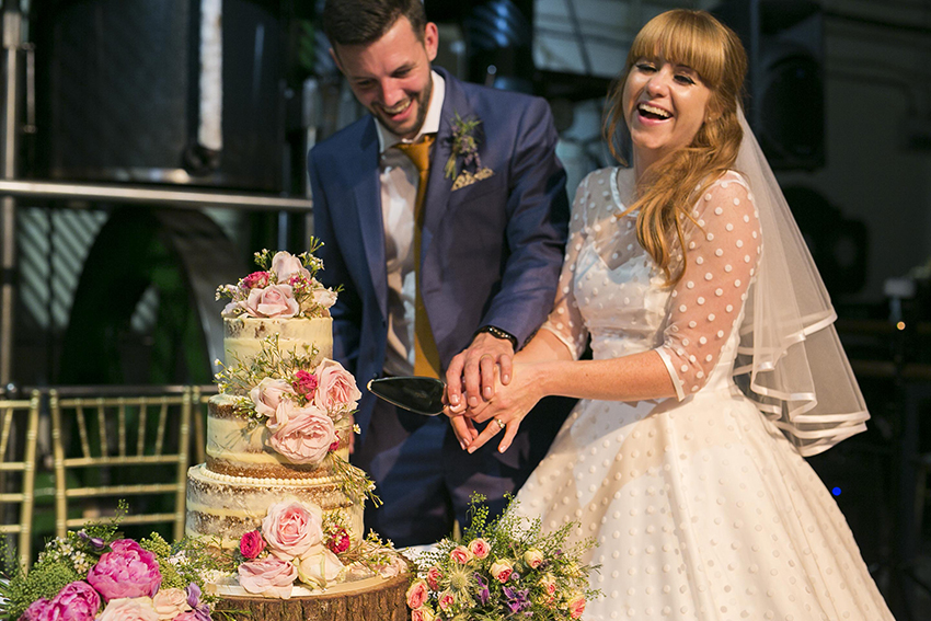 Couple cutting wedding cake in The Steam Hall, London Museum of Water & Steam.