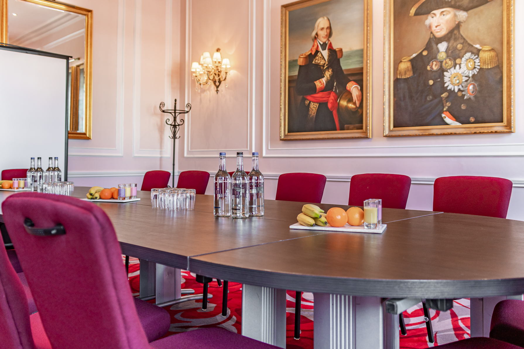 Elegant meeting room at The Trafalgar, featuring an oval table and plush red chairs.