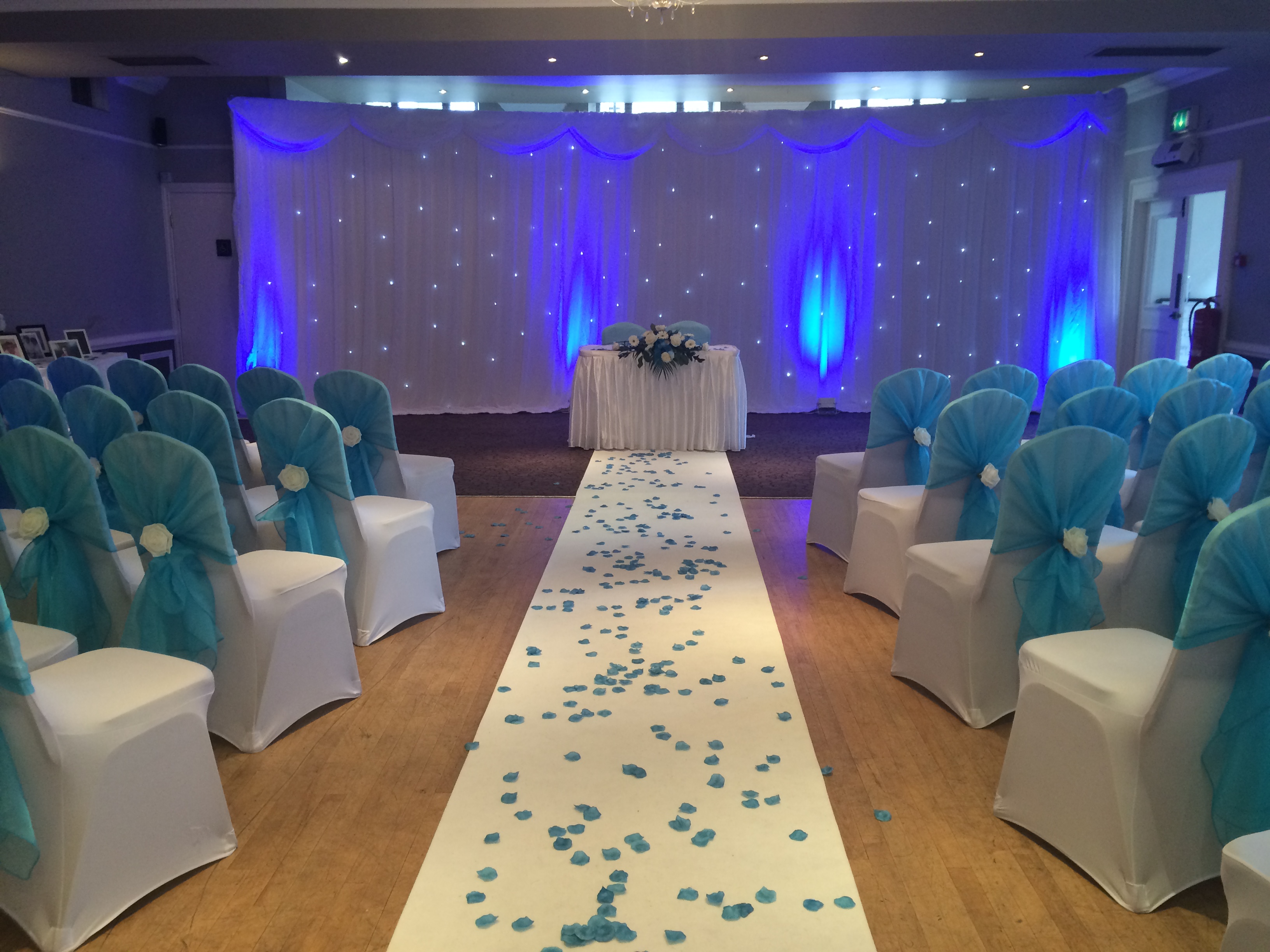 Elegant wedding venue at The Velasco, featuring soft blue lighting and petal-adorned aisle.