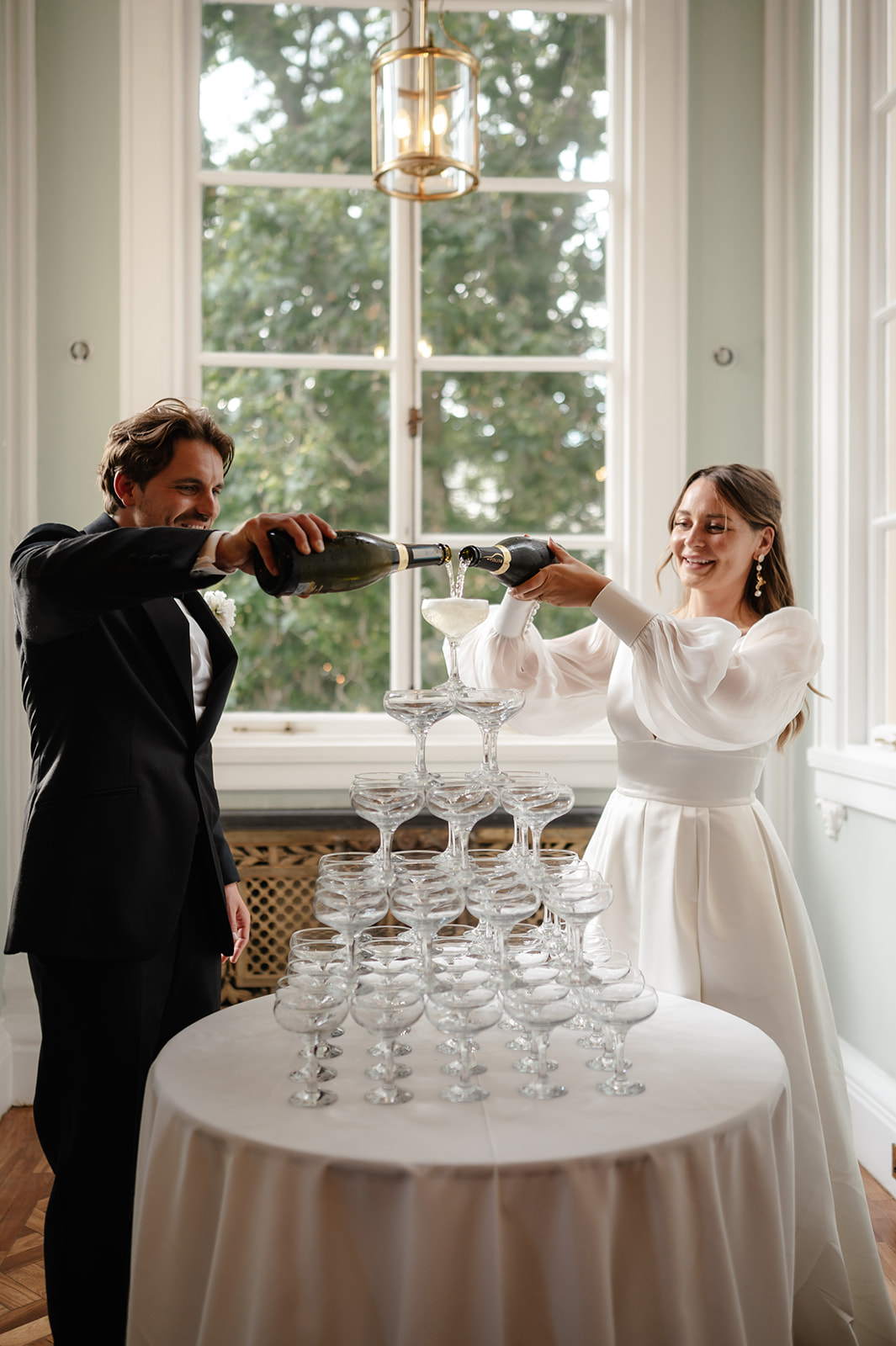 Couple pouring champagne in elegant Council Room, celebrating a sophisticated event.