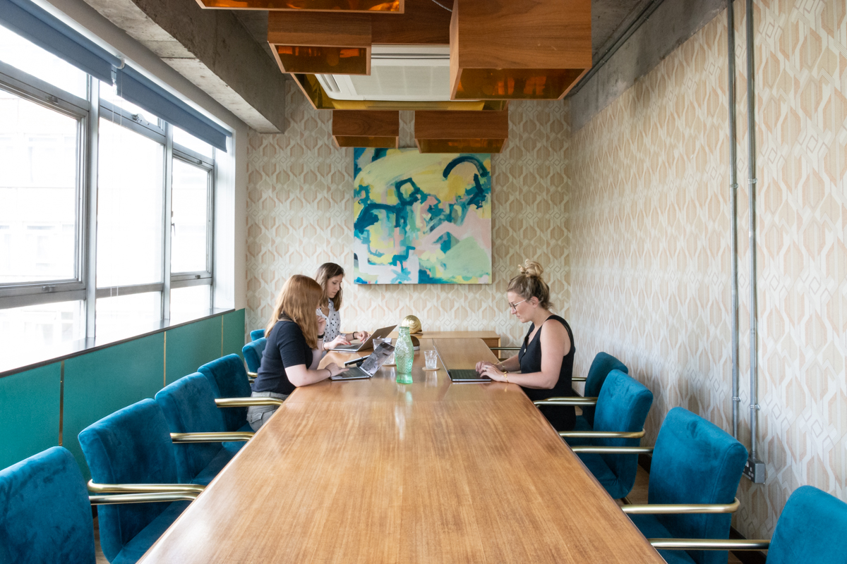 Modern meeting room with wooden table and teal chairs, perfect for brainstorming sessions.
