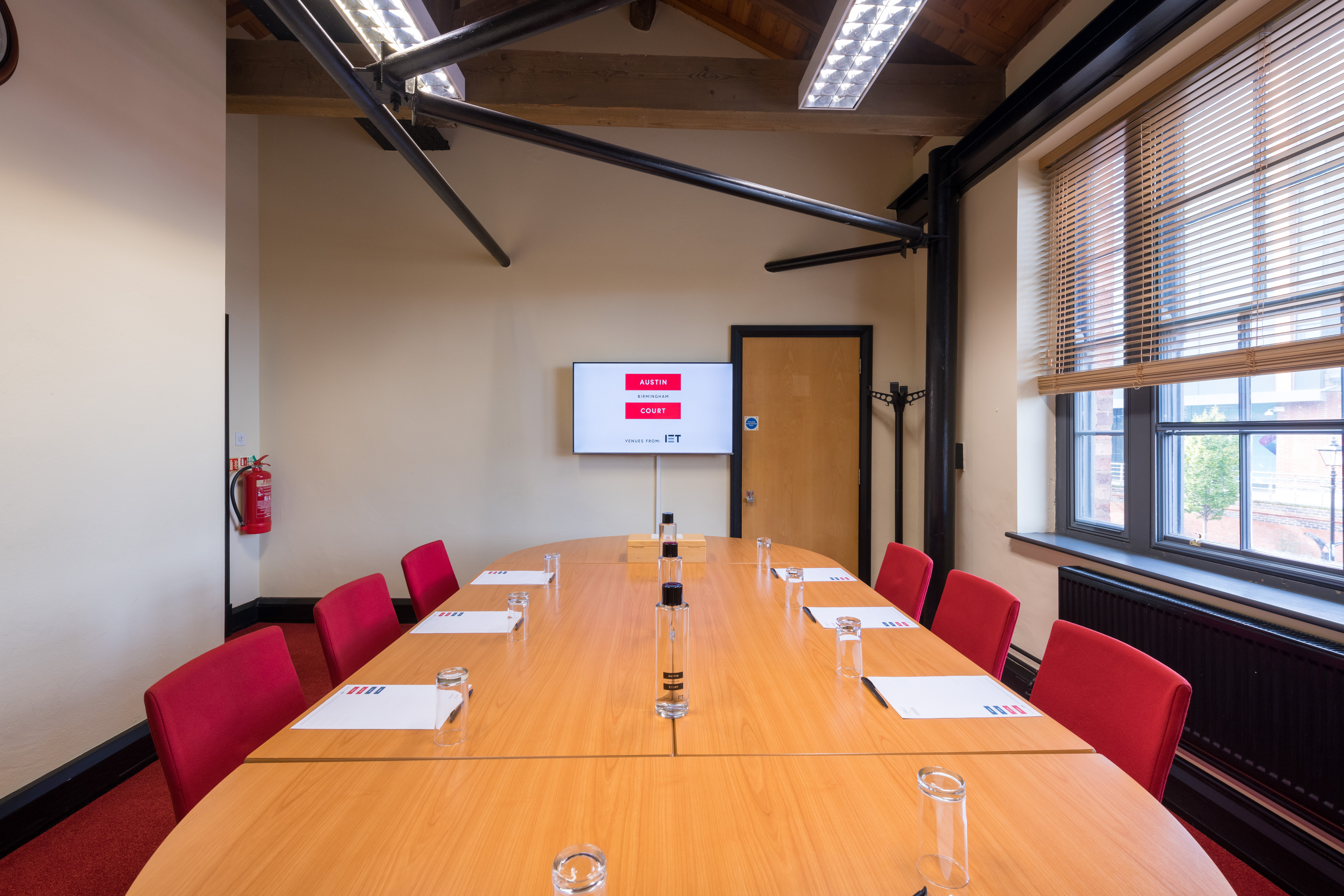 Boot Room at IET Birmingham: Austin Court, featuring a long table and red chairs for meetings.